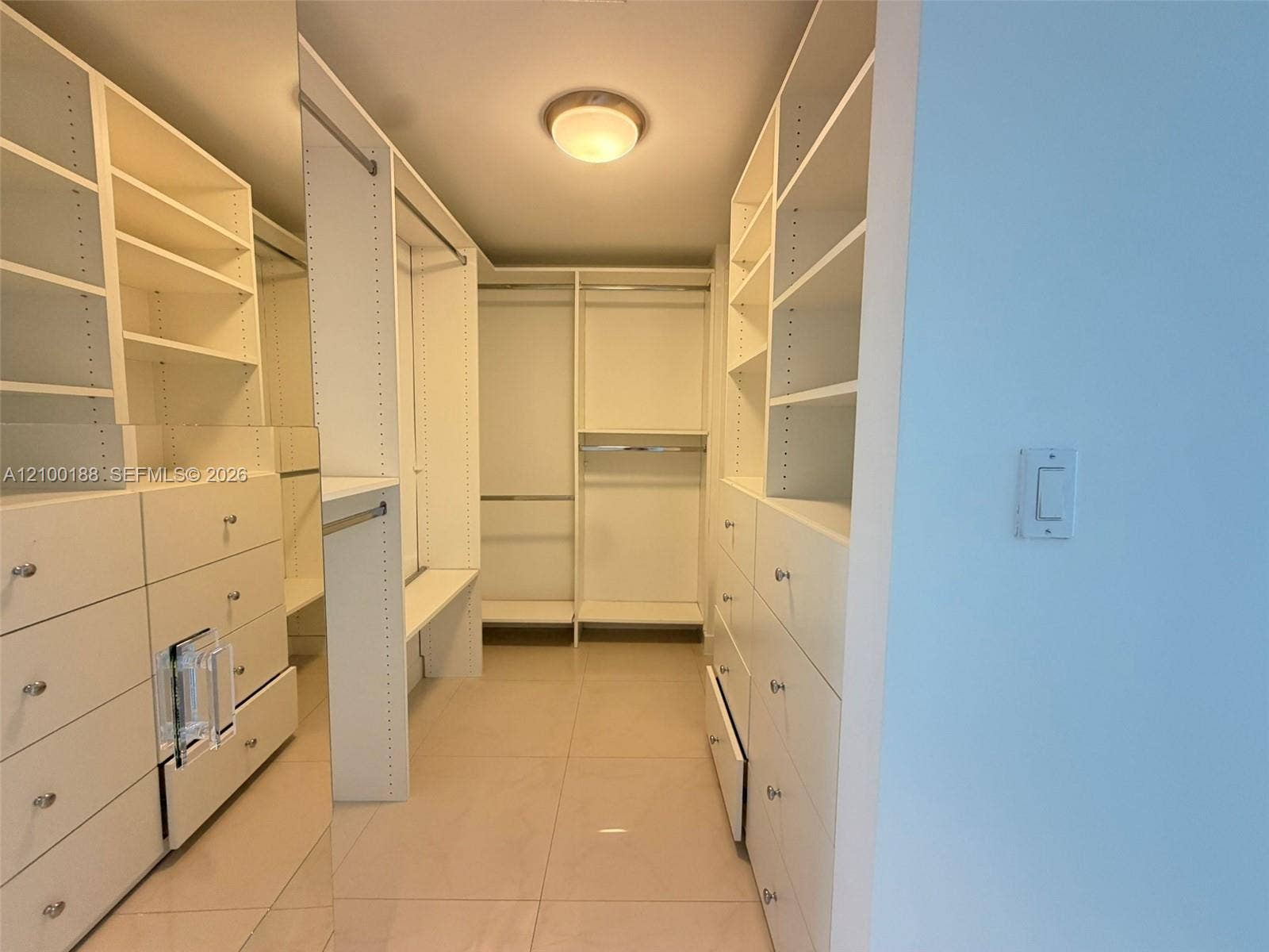 2821 N Ocean Boulevard, #305S, Fort Lauderdale, Fort Lauderdale, FL 33308 Custom walk-in closet featuring white built-in shelving, floor-to-ceiling cabinetry, integrated hanging rods, and neutral tile flooring