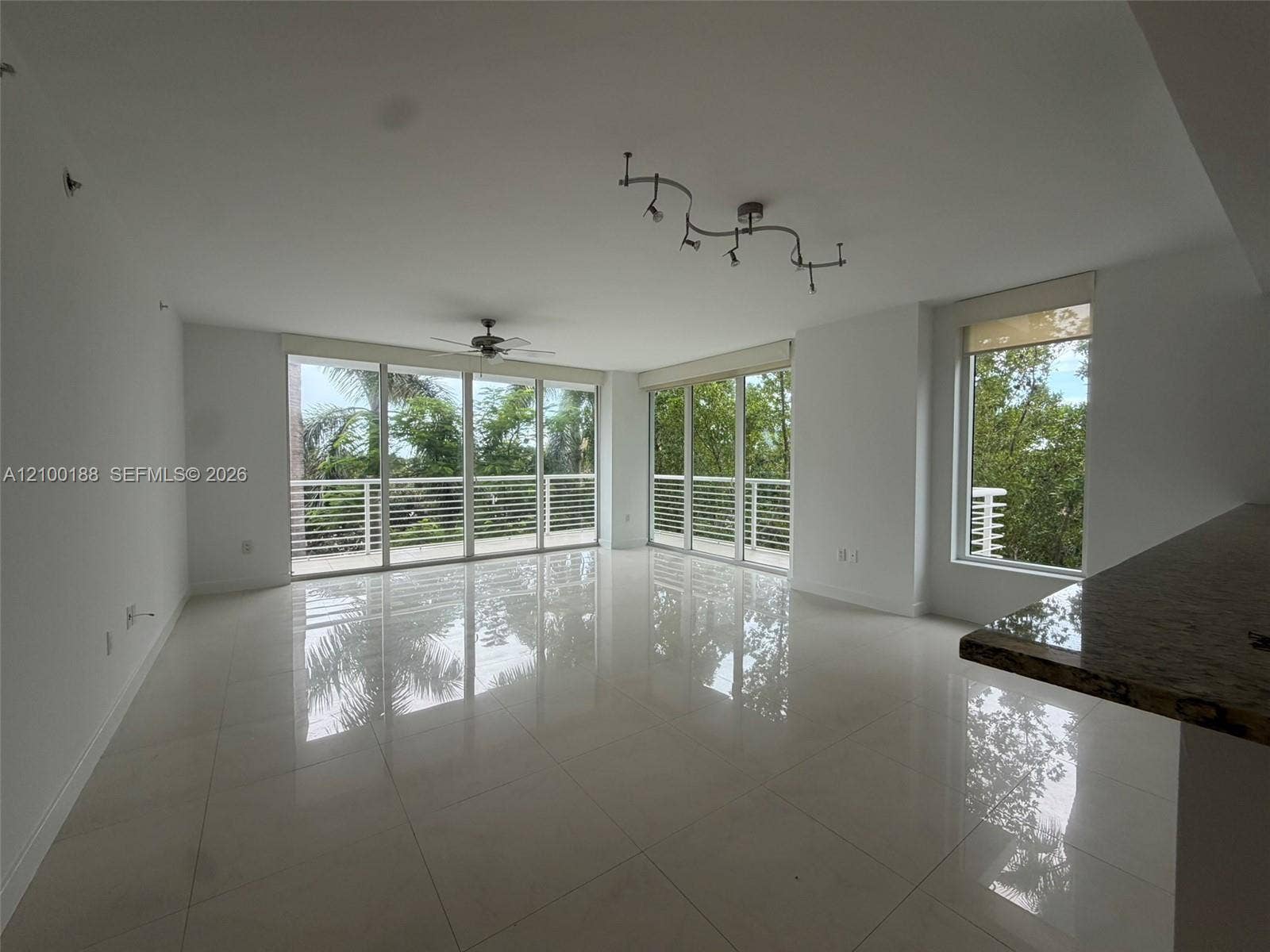 2821 N Ocean Boulevard, #305S, Fort Lauderdale, Fort Lauderdale, FL 33308 Open-concept interior featuring large-format tile flooring, expansive floor-to-ceiling glass sliding doors, integrated track lighting, a ceiling fan, and a built-in stone-top counter