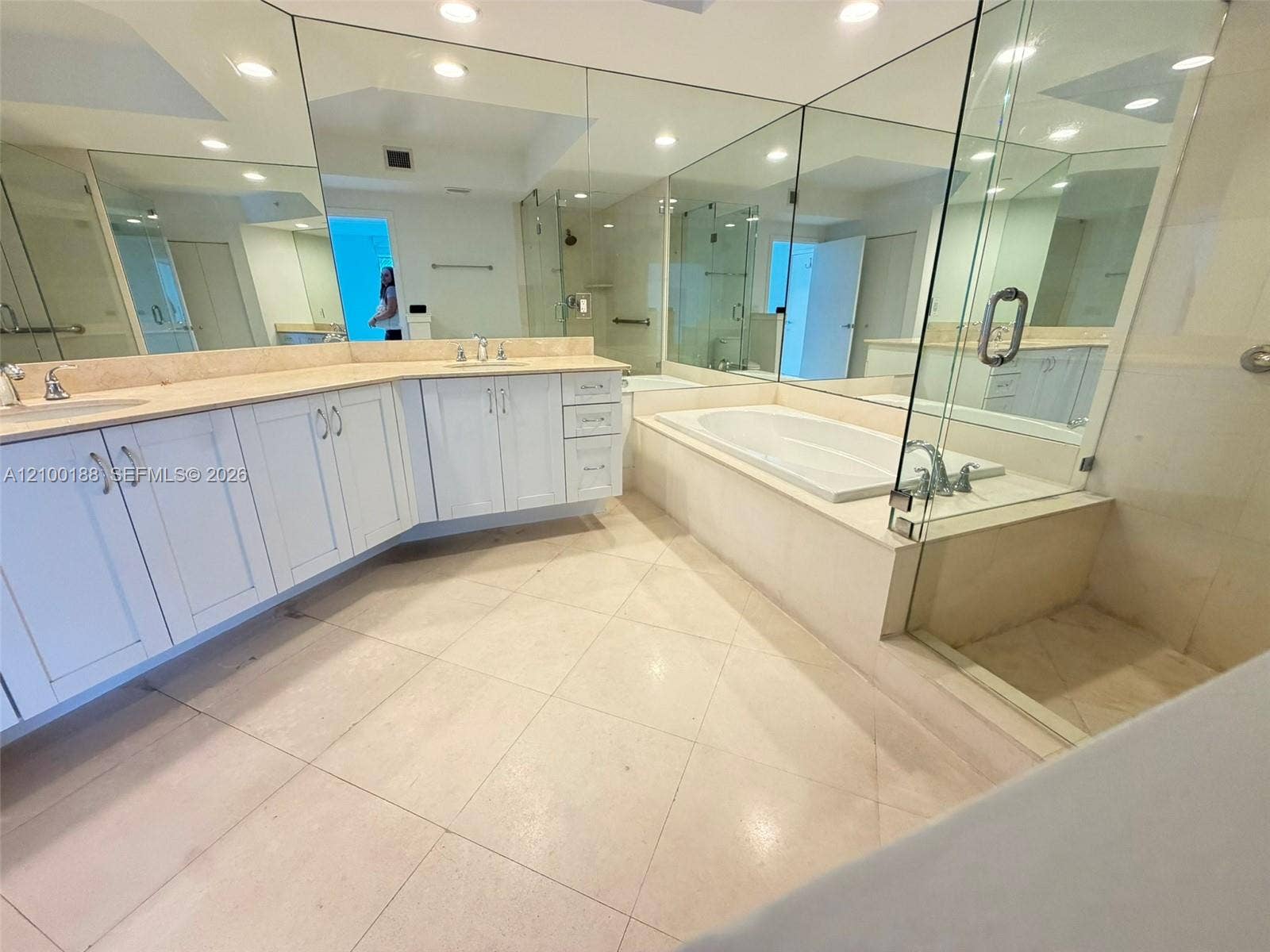 2821 N Ocean Boulevard, #305S, Fort Lauderdale, Fort Lauderdale, FL 33308 Bathroom featuring a double-sink vanity with white cabinetry and solid surface countertops, a built-in soaking tub, a glass-enclosed shower, expansive wall-to-wall mirrors, and large-format tile flooring