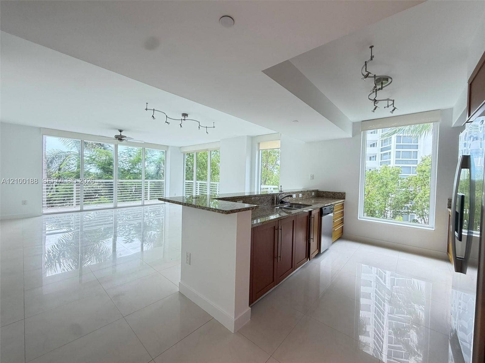 2821 N Ocean Boulevard, #305S, Fort Lauderdale, Fort Lauderdale, FL 33308 Open concept kitchen featuring stone countertops, wood-finish cabinetry, stainless steel appliances, large-format tile flooring, and floor-to-ceiling windows