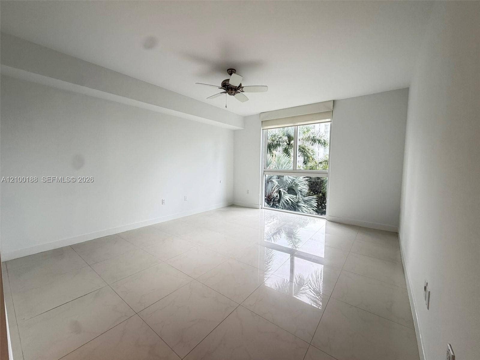 2821 N Ocean Boulevard, #305S, Fort Lauderdale, Fort Lauderdale, FL 33308 Neutral-toned room featuring large-format tile flooring, a ceiling fan, and a multi-pane window with exterior greenery