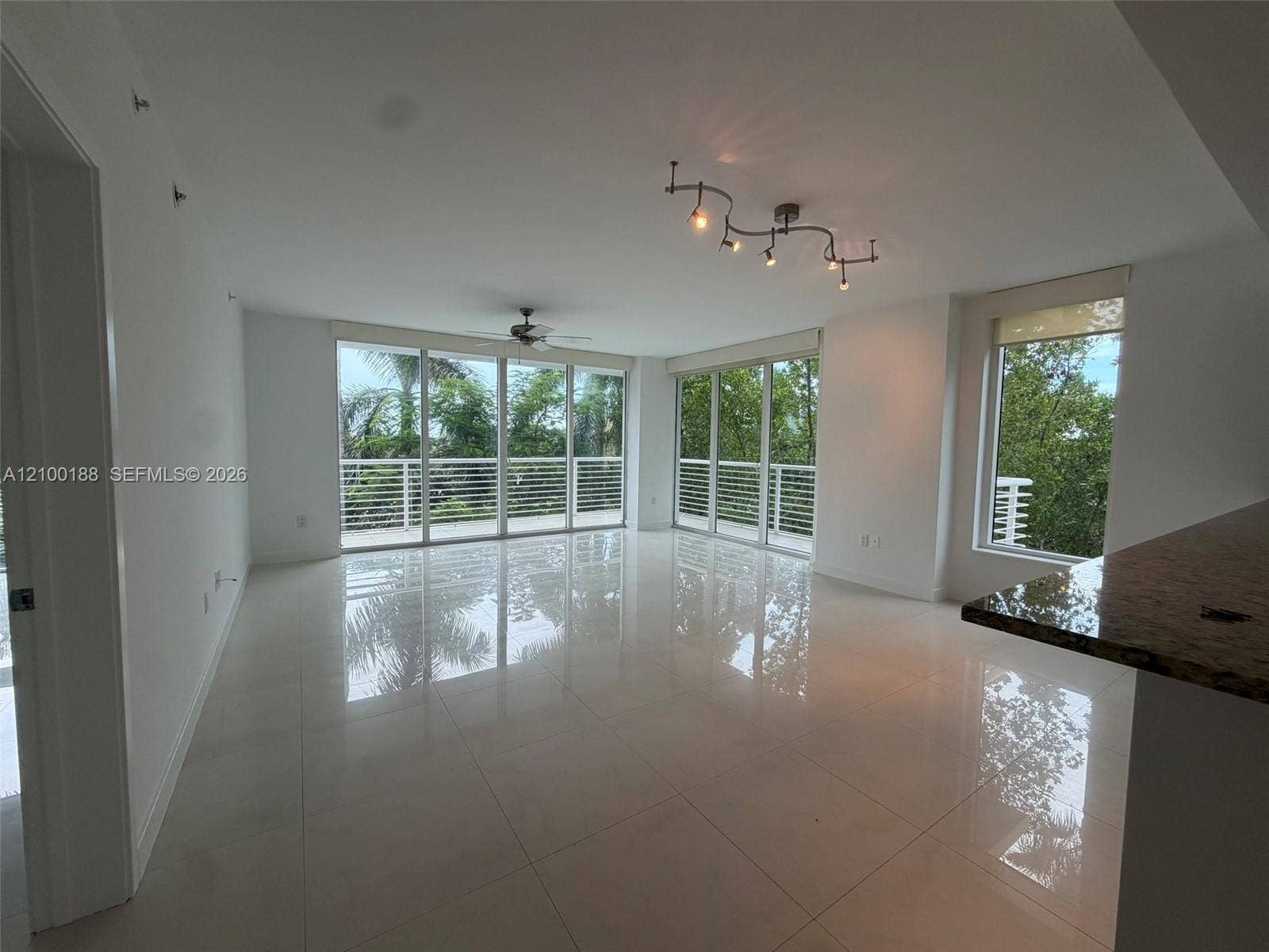 2821 N Ocean Boulevard, #305S, Fort Lauderdale, Fort Lauderdale, FL 33308 Open-concept interior featuring large-format tile flooring, expansive floor-to-ceiling windows, track lighting, a ceiling fan, and a stone-surface breakfast bar