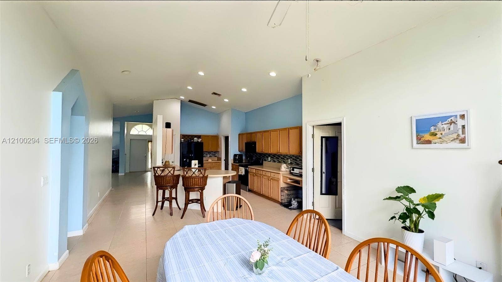 Open-concept interior featuring vaulted ceilings recessed lighting, tile flooring, and a kitchen equipped with wood cabinetry and a peninsula counter