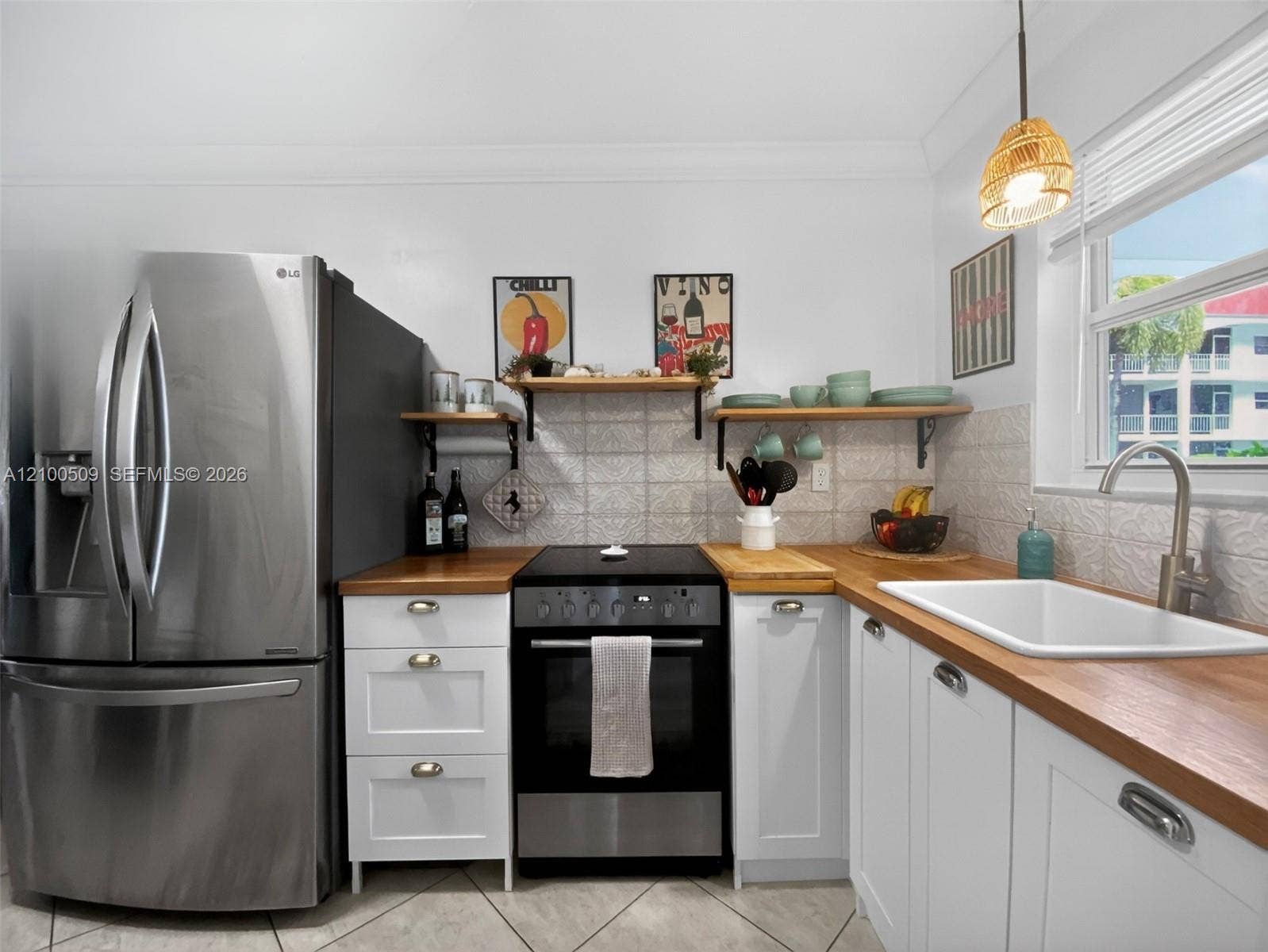 White cabinetry with wood-finish countertops, stainless steel appliances, and a tile backsplash