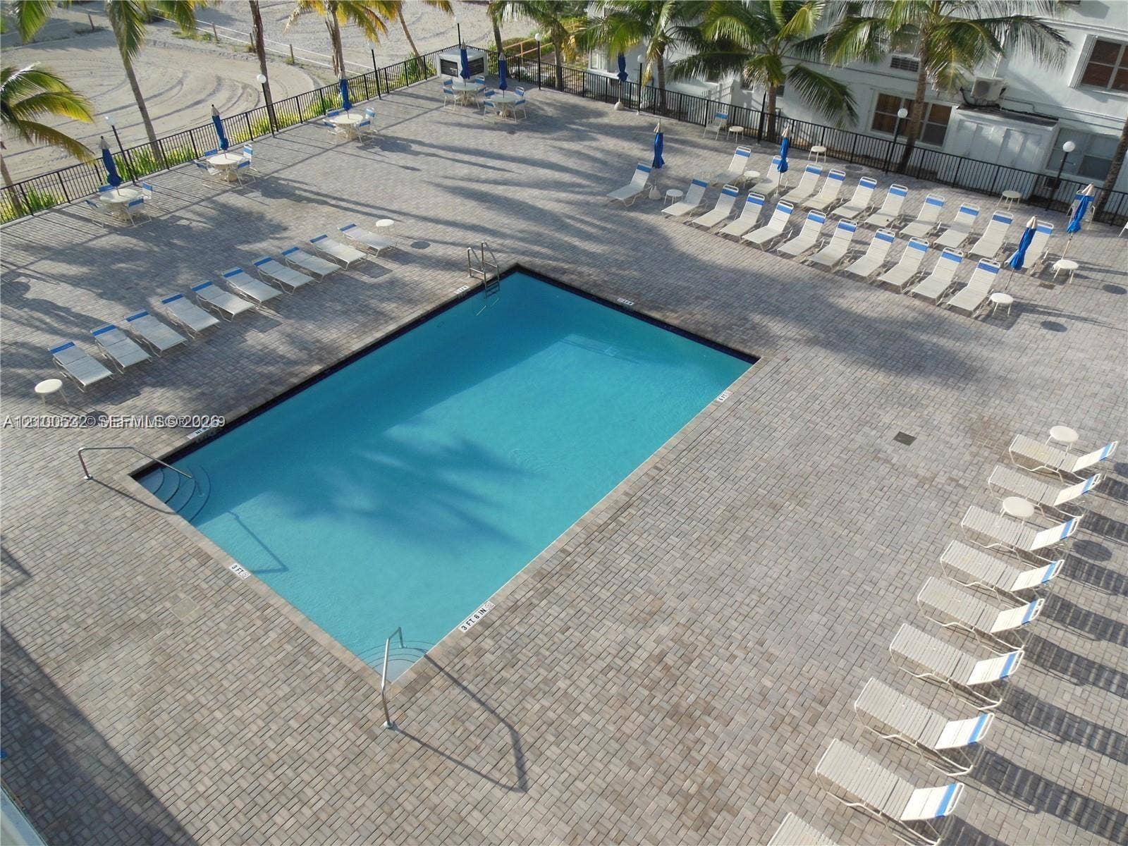 9273 Collins Avenue, #912, Surfside, Surfside, FL 33154 Rectangular swimming pool featuring stone paver decking, metal perimeter fencing, and integrated pool stairs