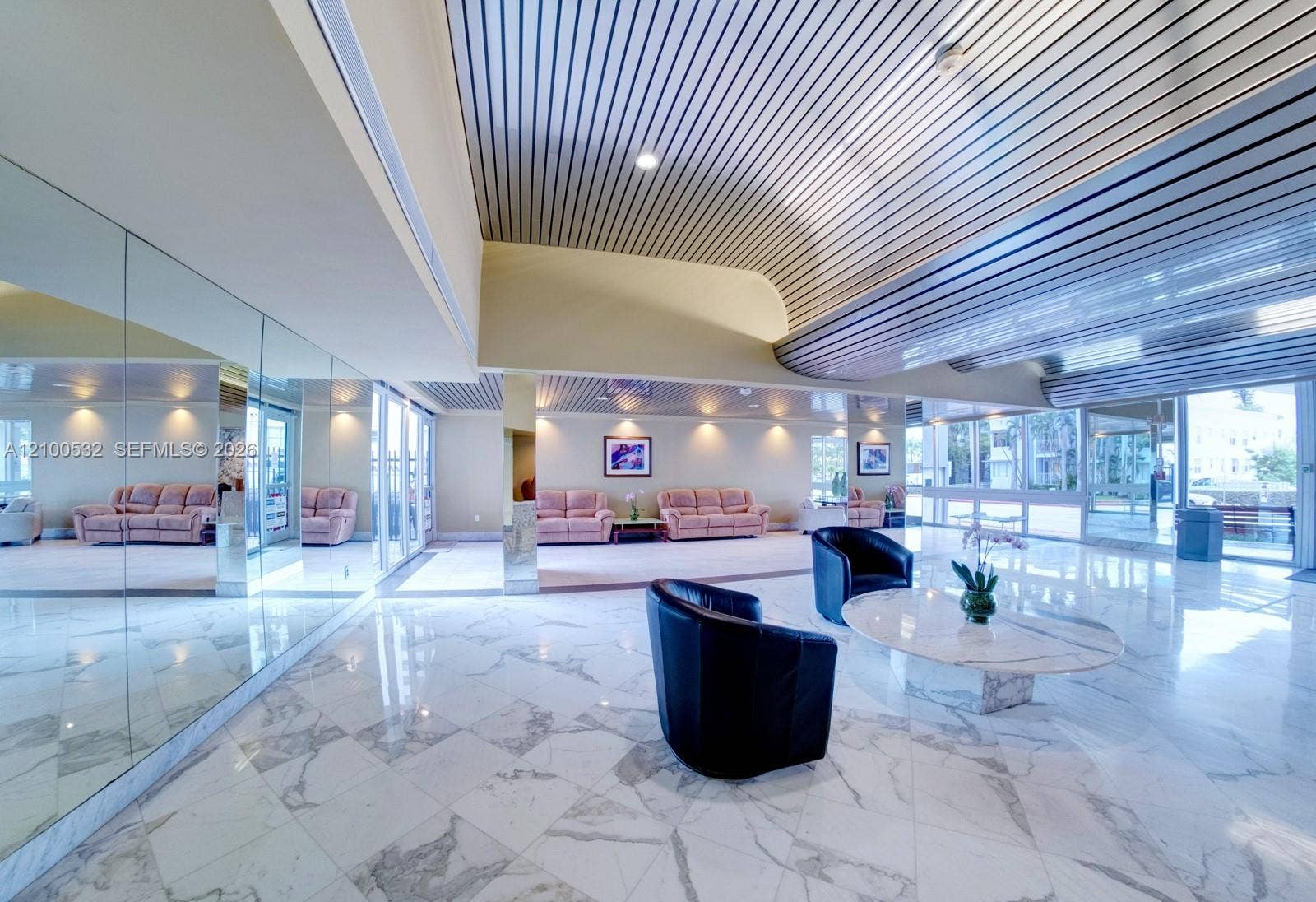 9273 Collins Avenue, #912, Surfside, Surfside, FL 33154 Polished stone flooring, mirrored wall panels, linear metal ceiling detailing, and recessed LED lighting