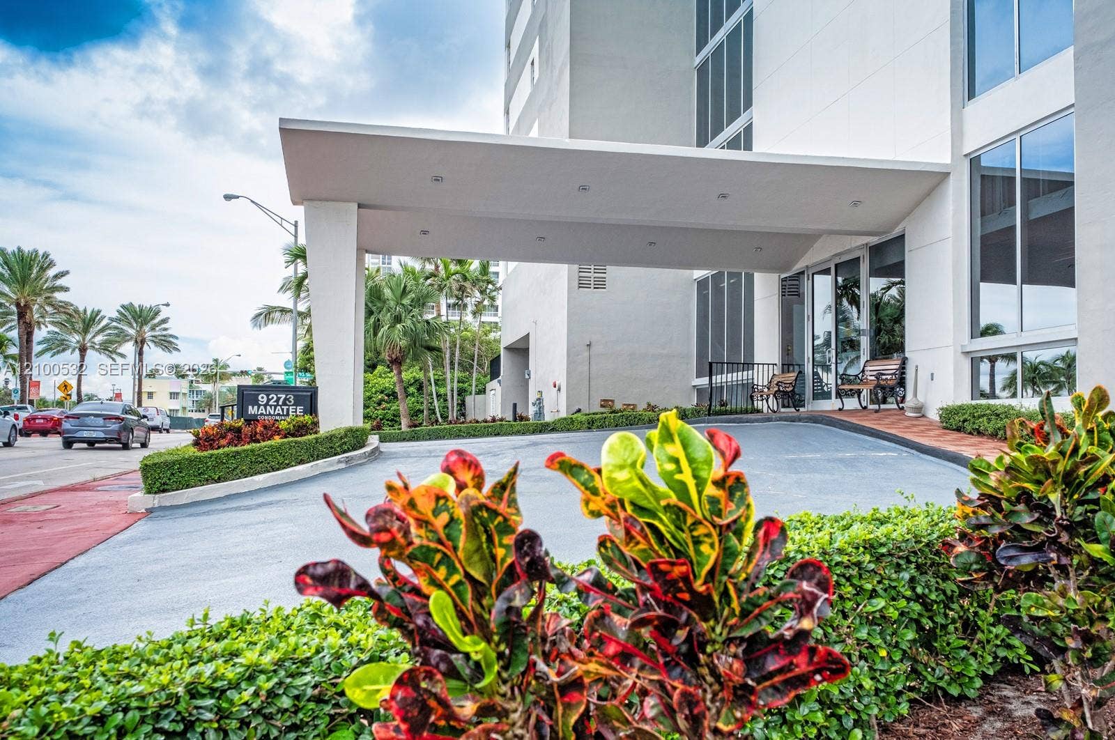 9273 Collins Avenue, #912, Surfside, Surfside, FL 33154 Covered porte-cochre entry featuring recessed lighting, glass-paneled entrance doors, multi-story building facade, and manicured landscaping