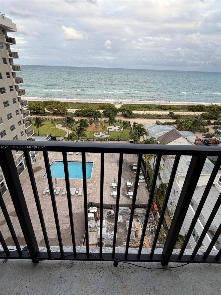 9273 Collins Avenue, #912, Surfside, Surfside, FL 33154 Balcony featuring a black metal railing, overlooking a swimming pool, landscaped grounds, and the ocean shoreline