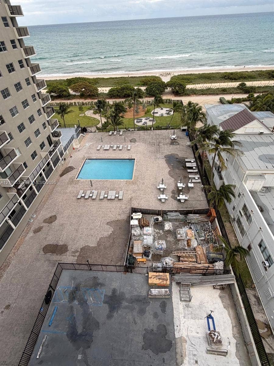 9273 Collins Avenue, #912, Surfside, Surfside, FL 33154 Outdoor pool area featuring a paved deck, palm trees, and direct proximity to the oceanfront