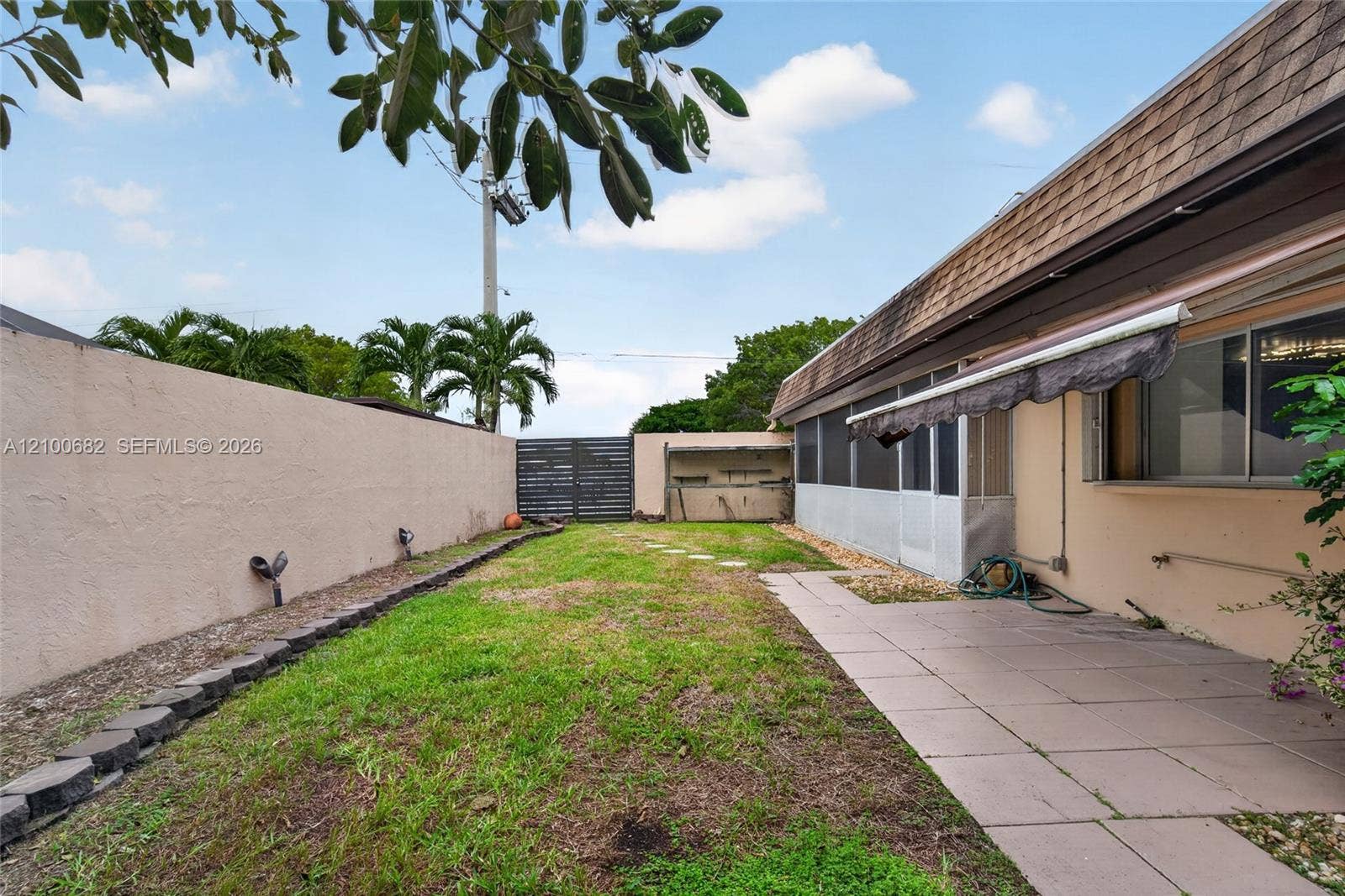 8402 SW 102nd Court, Miami, FL 33173 Back yard featuring a concrete paver patio, screened-in enclosed patio, perimeter privacy wall, and newer horizontal slat gate*