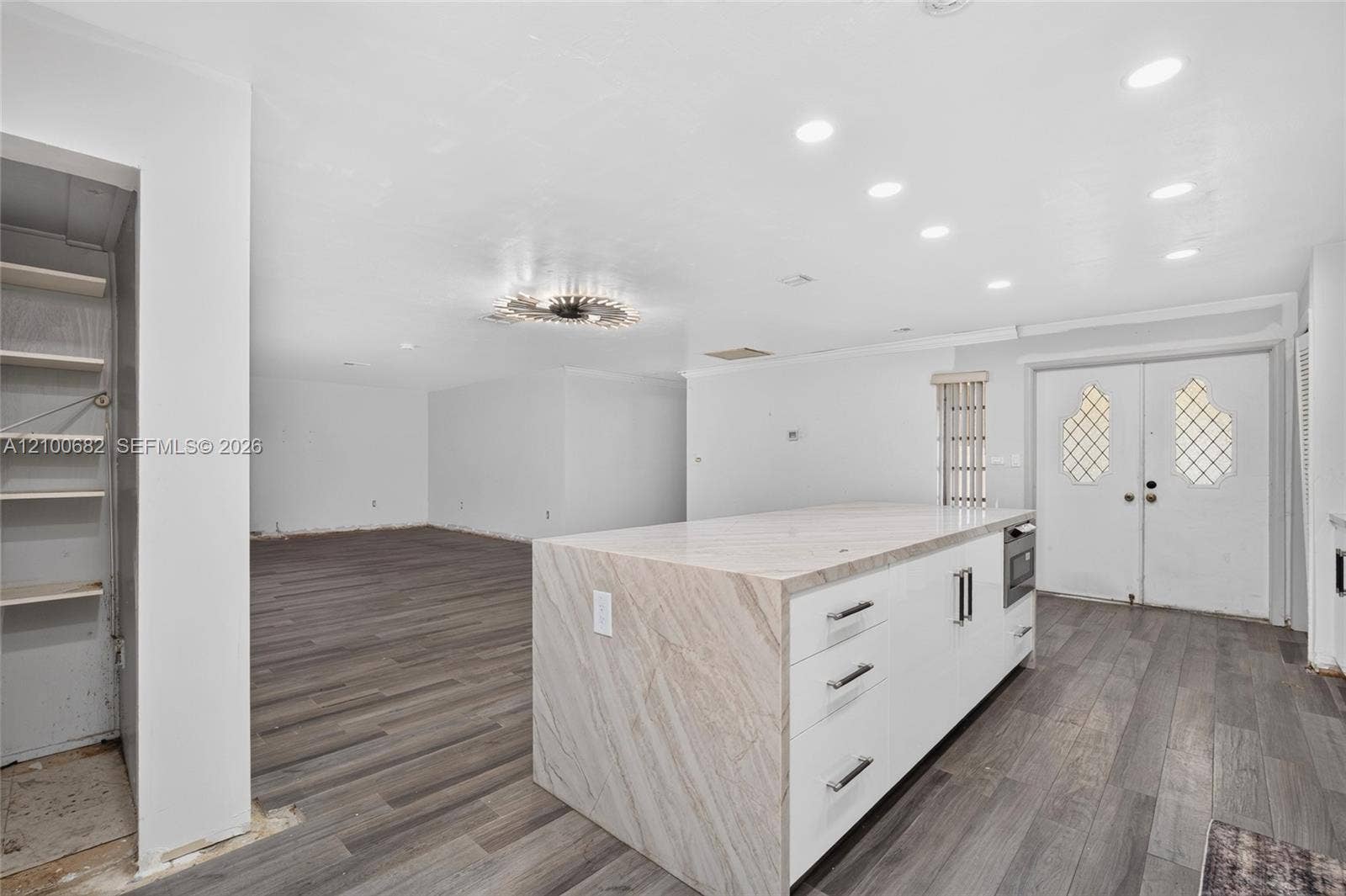 8402 SW 102nd Court, Miami, FL 33173 Expansive room featuring vinyl wood-finish flooring, a large kitchen island with stone-finish countertop & microwave, recessed lighting, double-door entryway, deep pantry on the side *