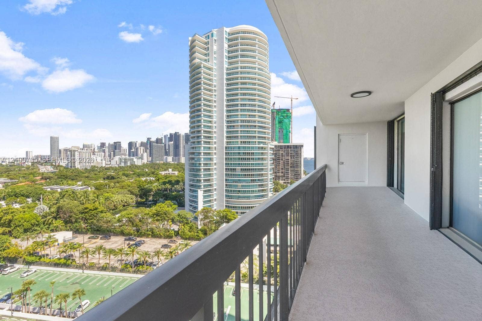 Covered private balcony featuring a neutral concrete floor, solid railing, and a flush-mount ceiling light