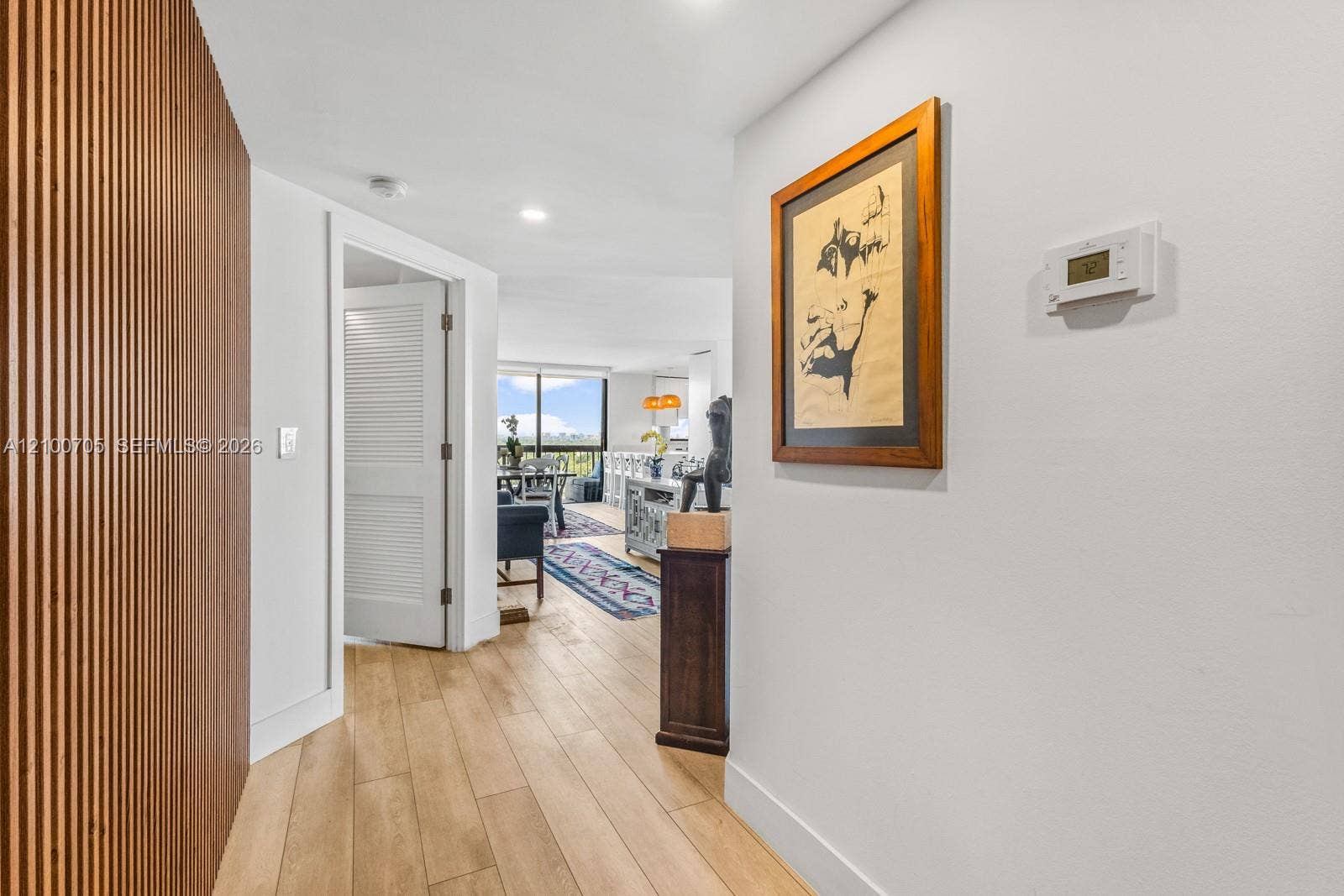 Interior hallway featuring a floor-to-ceiling vertical wood slat accent wall, recessed lighting, and wood-finish flooring