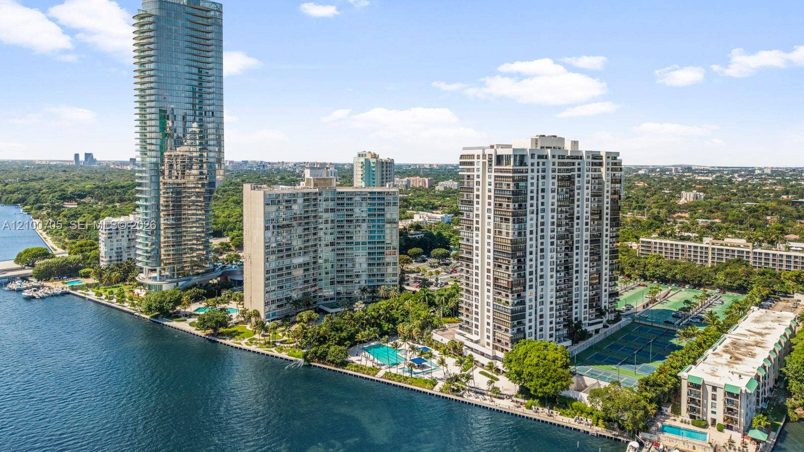 Waterfront high-rise community featuring multiple swimming pools, tennis courts, and concrete seawall bulkhead