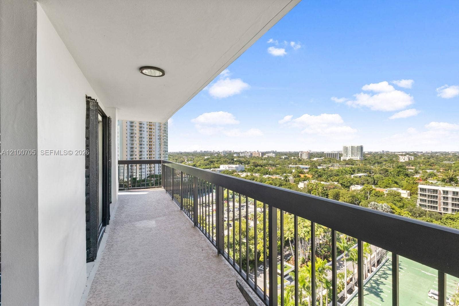Covered balcony featuring textured flooring, recessed lighting, and a black metal railing