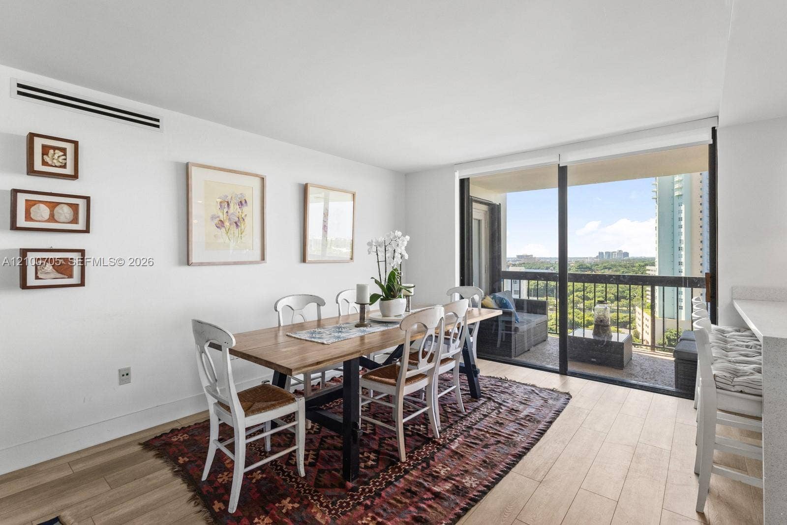 Dining area featuring wood-finish flooring, floor-to-ceiling sliding glass doors, and access to an exterior balcony