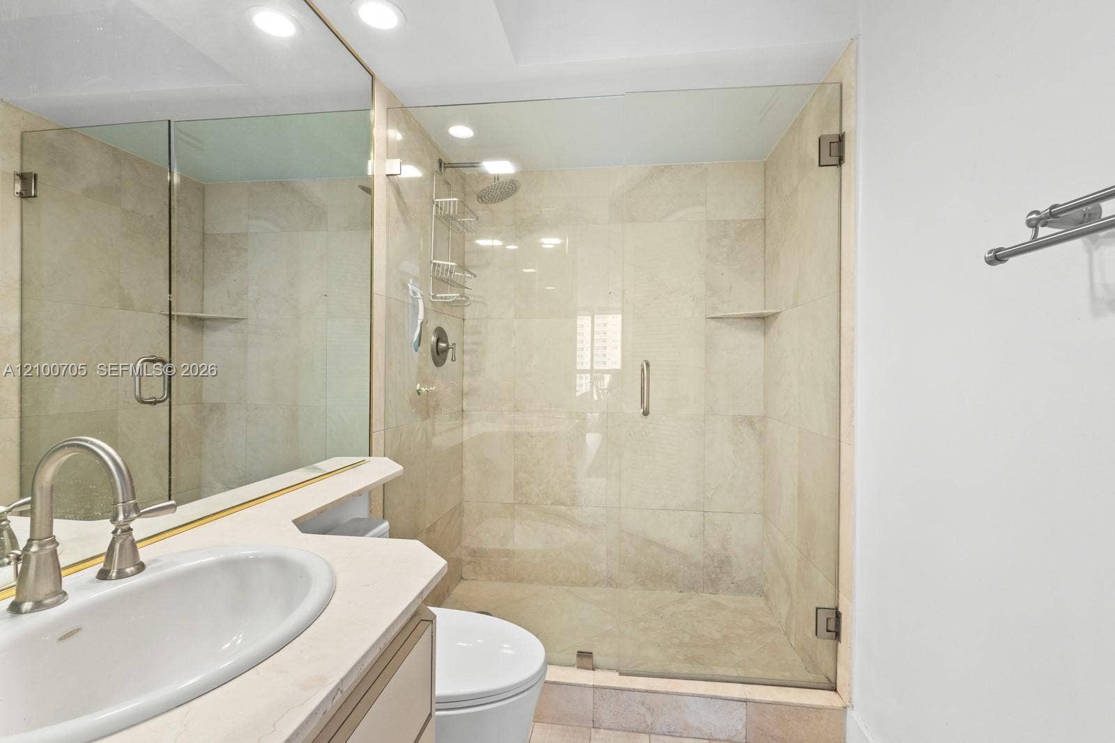 Walk-in shower with floor-to-ceiling neutral tile, glass enclosure, recessed lighting, and vanity with stone countertop