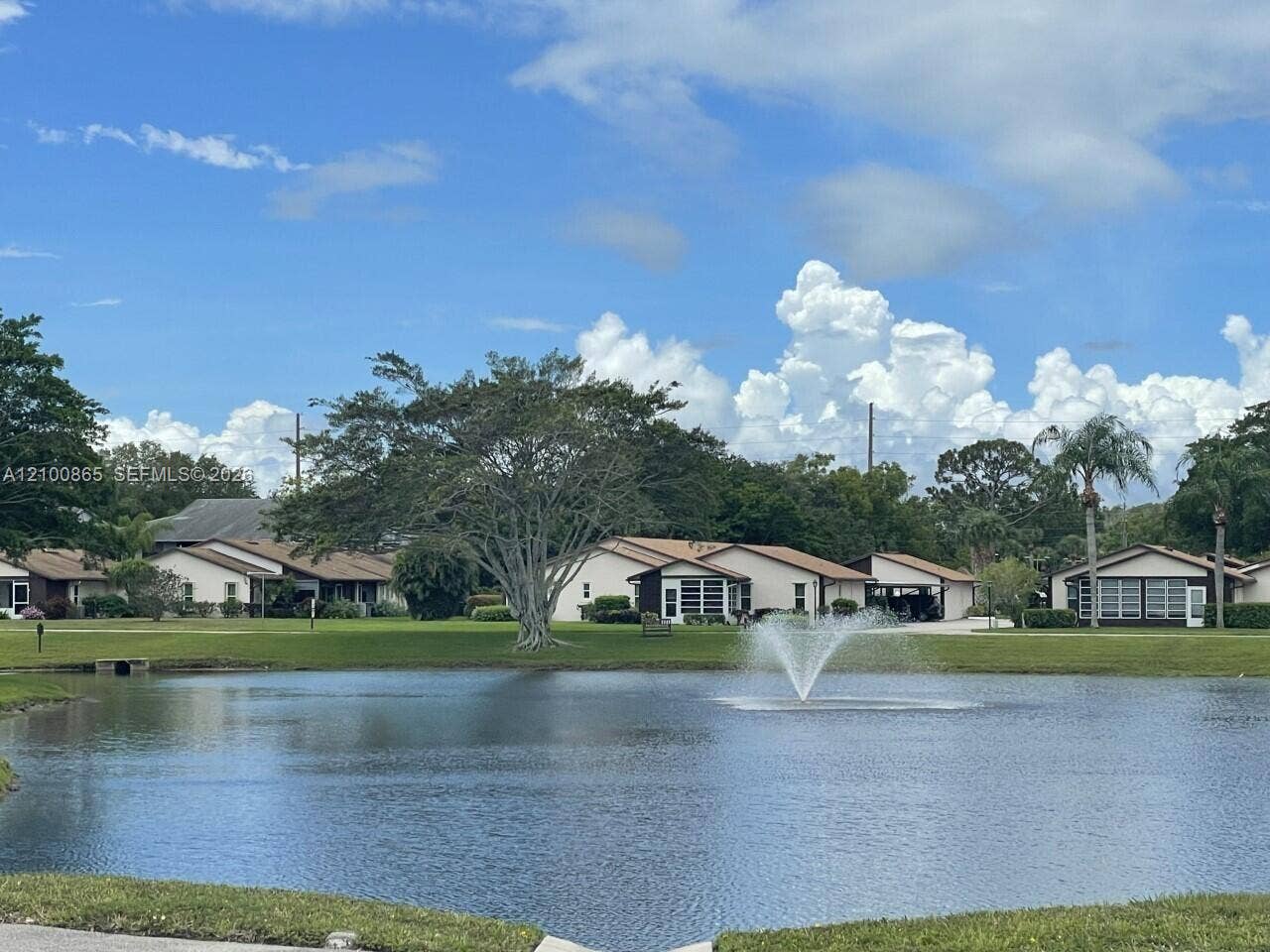 6531 SE Federal Highway, #J112, Stuart, FL 34997 Waterfront pond featuring a central fountain, expansive manicured lawn, and mature trees