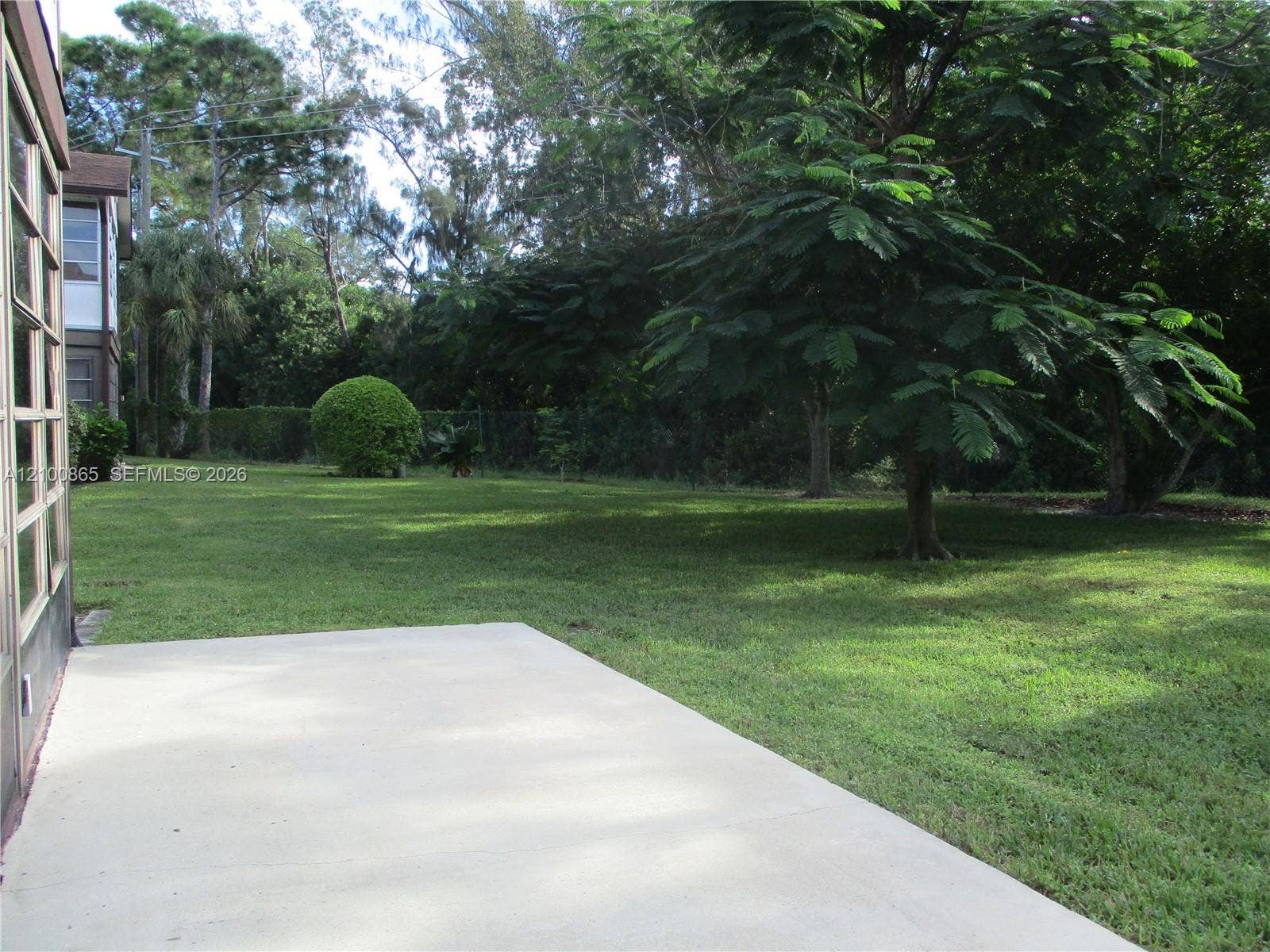 6531 SE Federal Highway, #J112, Stuart, FL 34997 Exterior concrete patio platform, Expansive green lawn with mature trees and a manicured hedge