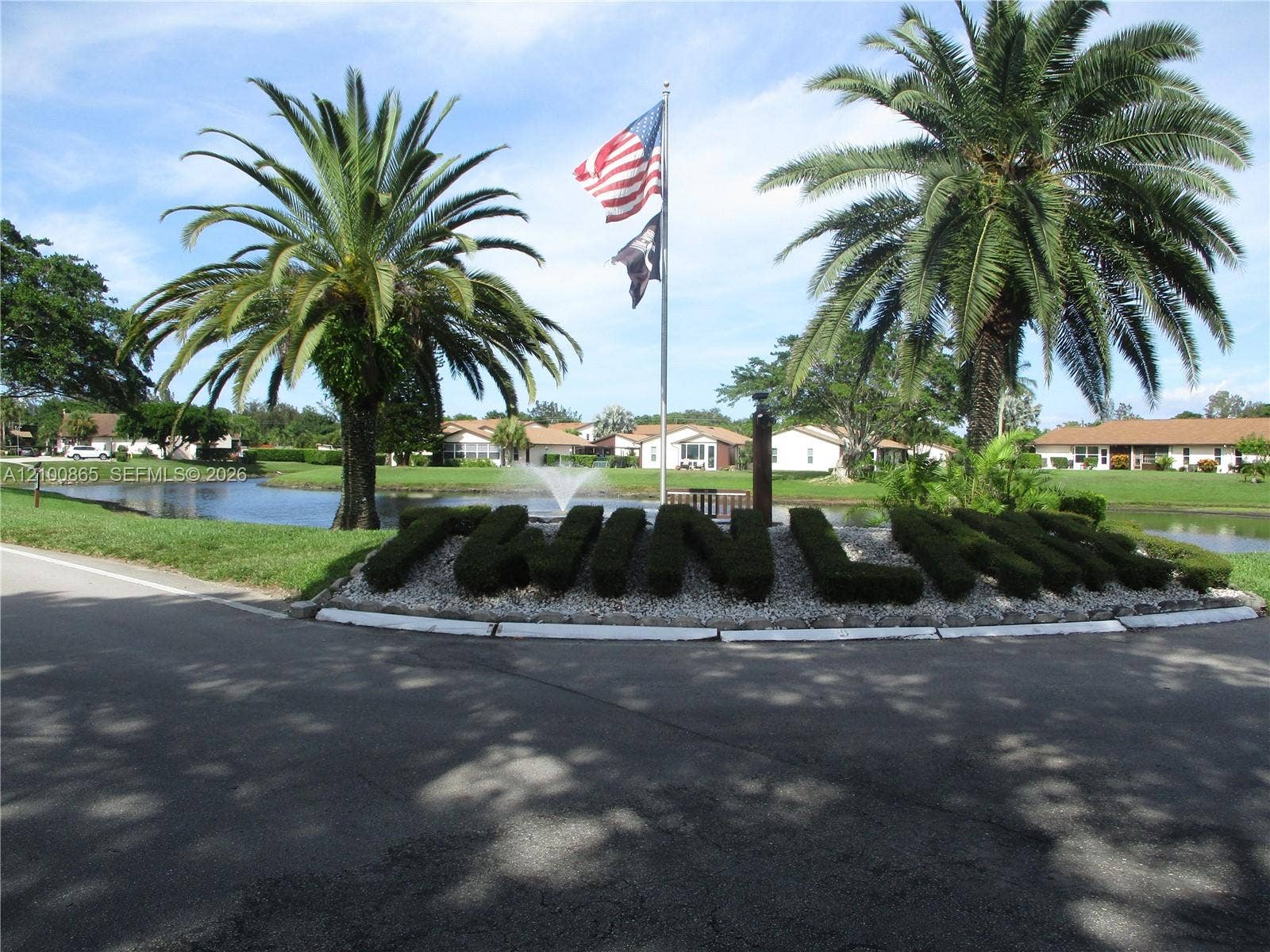 6531 SE Federal Highway, #J112, Stuart, FL 34997 Community entrance featuring shaped shrubbery, palm trees, a central fountain, and a water feature