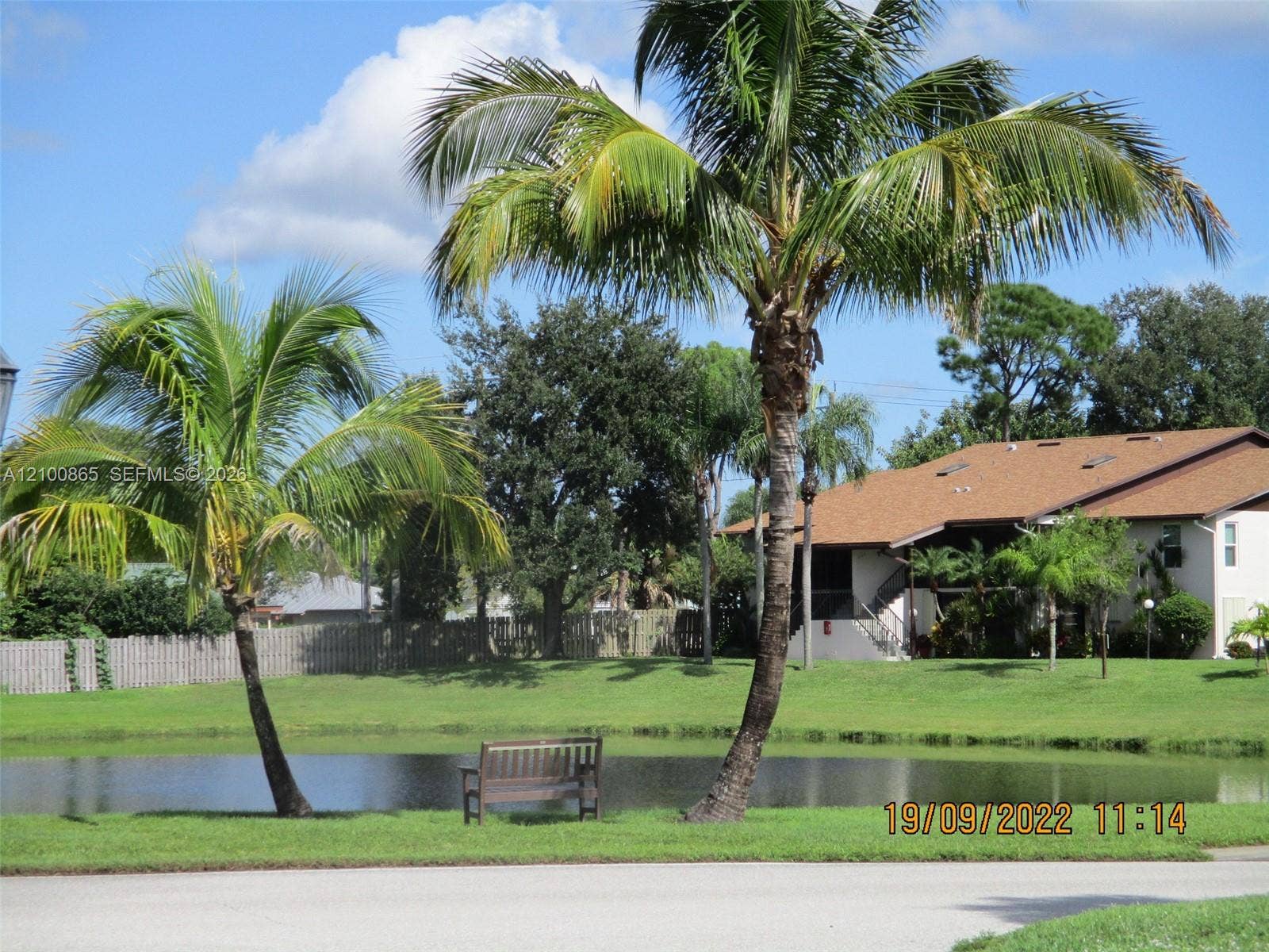 6531 SE Federal Highway, #J112, Stuart, FL 34997 Waterfront lot featuring mature palm trees, a manicured lawn, and perimeter fencing