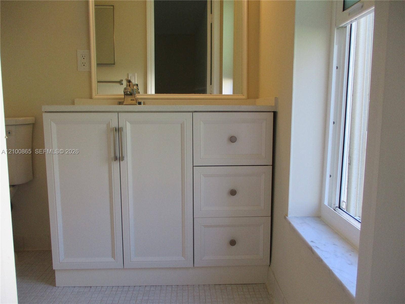 6531 SE Federal Highway, #J112, Stuart, FL 34997 Master bathroom White cabinetry with brushed metal hardware, stone-top vanity, mirror with a white frame, and stone window sill