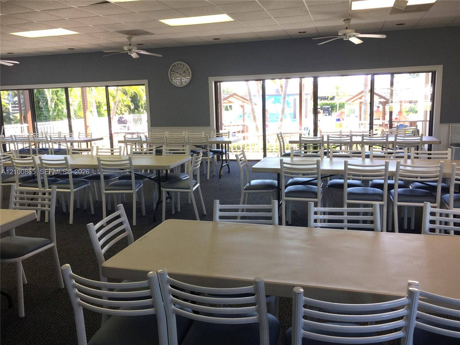 6531 SE Federal Highway, #J112, Stuart, FL 34997 community room with Spacious interior featuring recessed lighting, dual ceiling fans, wall-to-wall carpeting, and multiple floor-to-ceiling sliding glass doors out to the pool