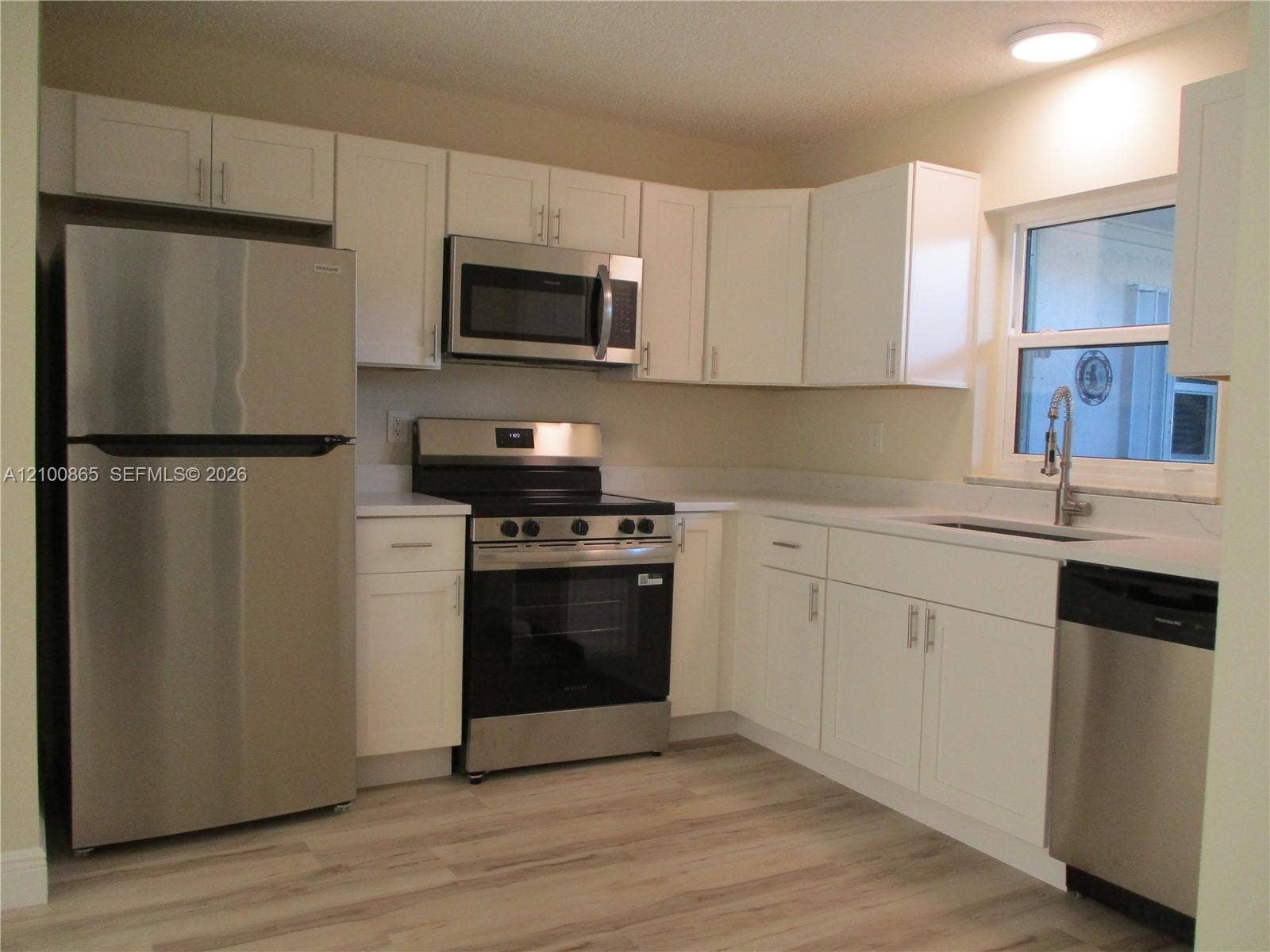 6531 SE Federal Highway, #J112, Stuart, FL 34997 Kitchen featuring white shaker-style cabinetry, stainless steel appliances, granite countertops