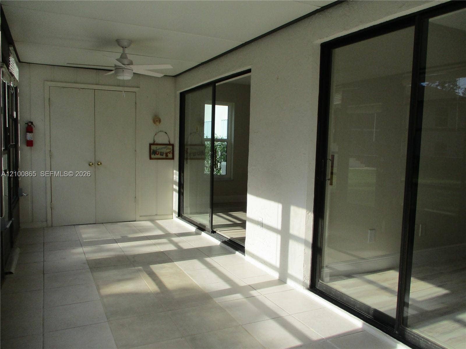 6531 SE Federal Highway, #J112, Stuart, FL 34997 Tiled flooring with large format tiles, sliding glass doors with black frames, white ceiling fan, and built-in closet with bifold doors. Slidering door into the living area and master bedroom