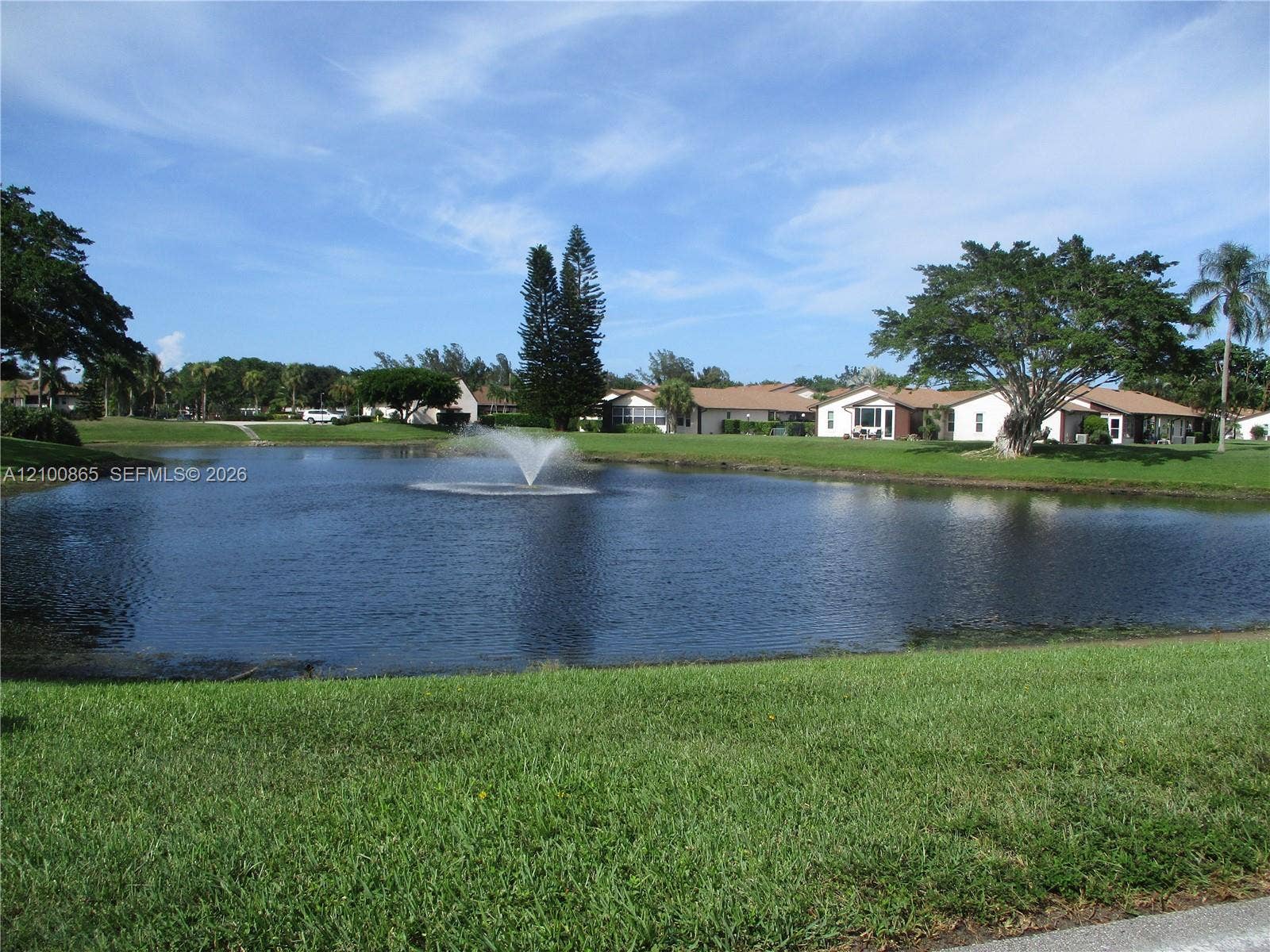 6531 SE Federal Highway, #J112, Stuart, FL 34997 Waterfront pond featuring a center fountain, surrounding manicured grass lawn, and mature trees