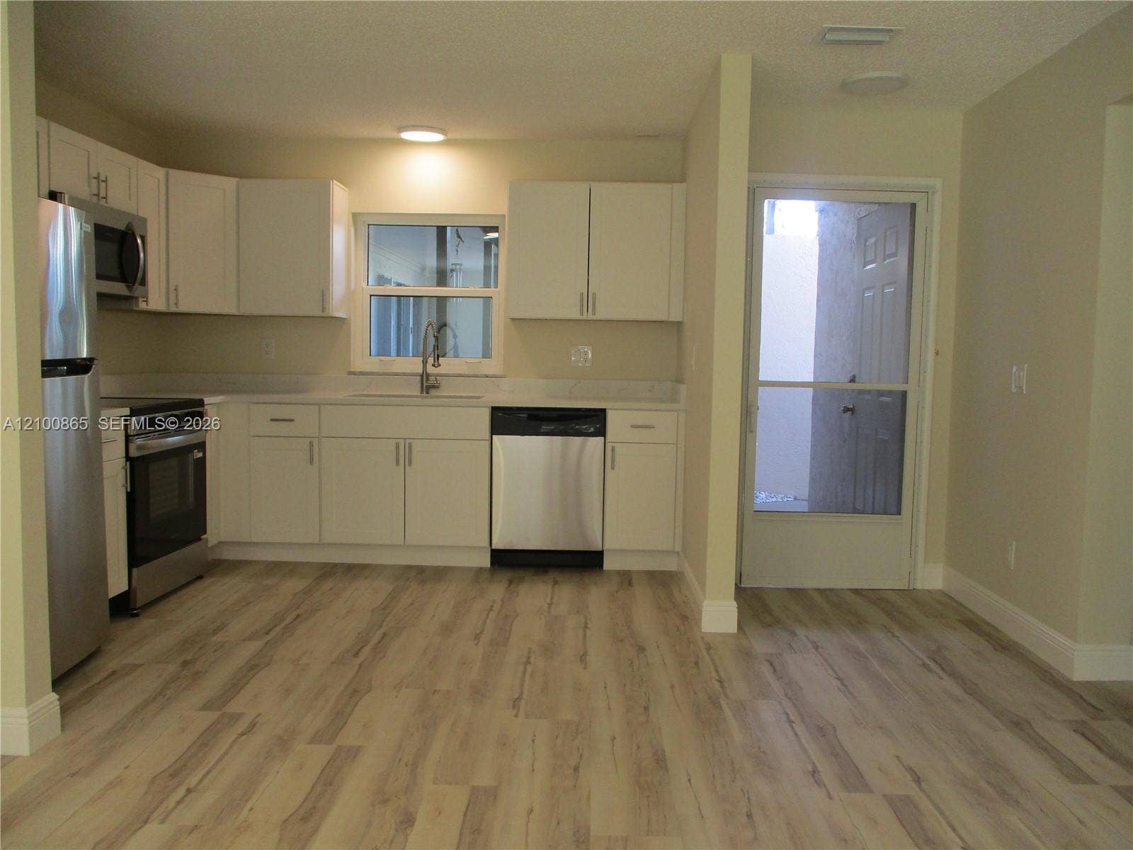 6531 SE Federal Highway, #J112, Stuart, FL 34997 Kitchen featuring white cabinetry, stainless steel appliances, and an exterior door with a screen