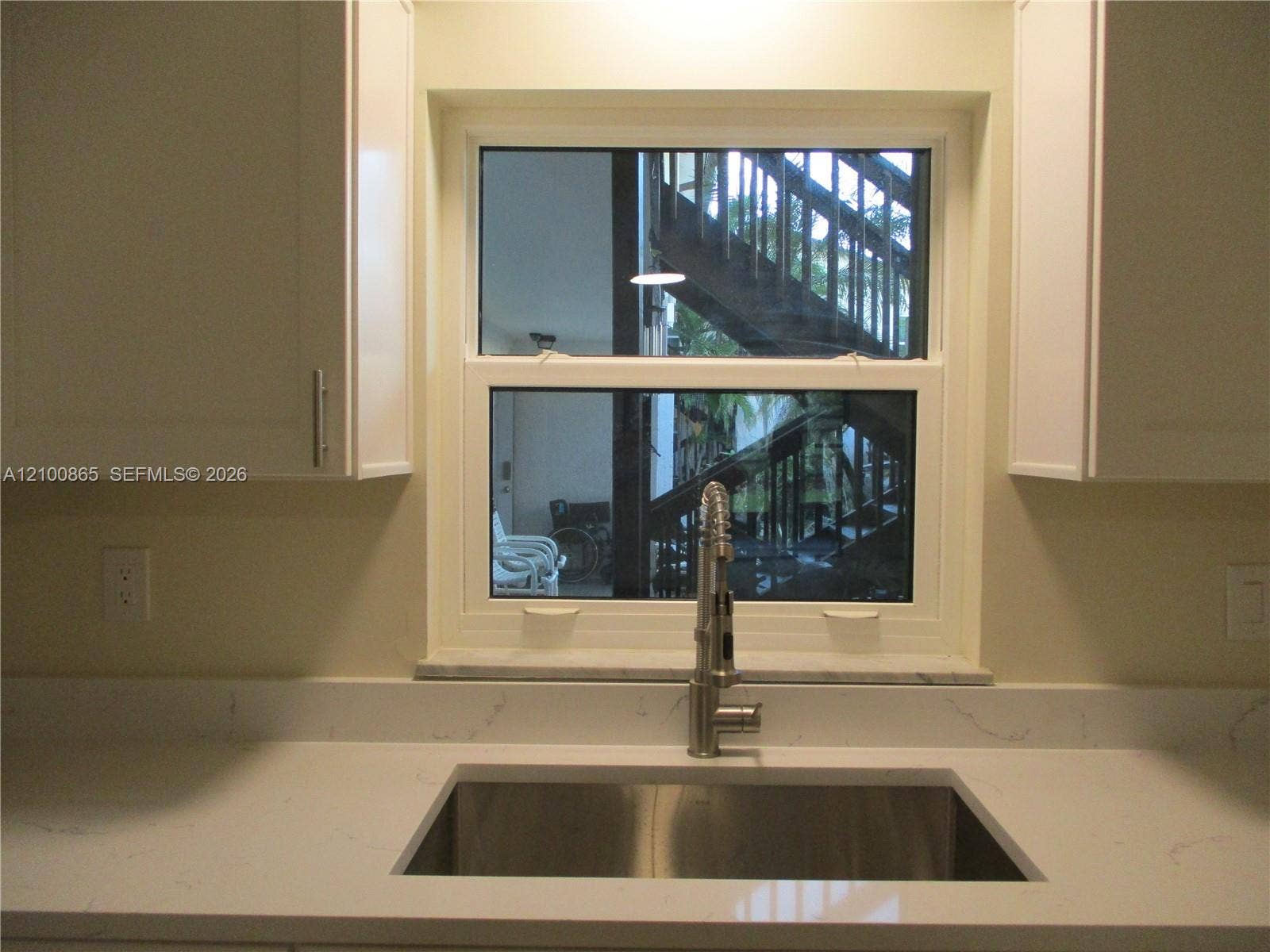 6531 SE Federal Highway, #J112, Stuart, FL 34997 Stainless steel undermount sink with a high-arch pull-down faucet, white stone-finish countertops with integrated backsplash, and shaker-style cabinetry