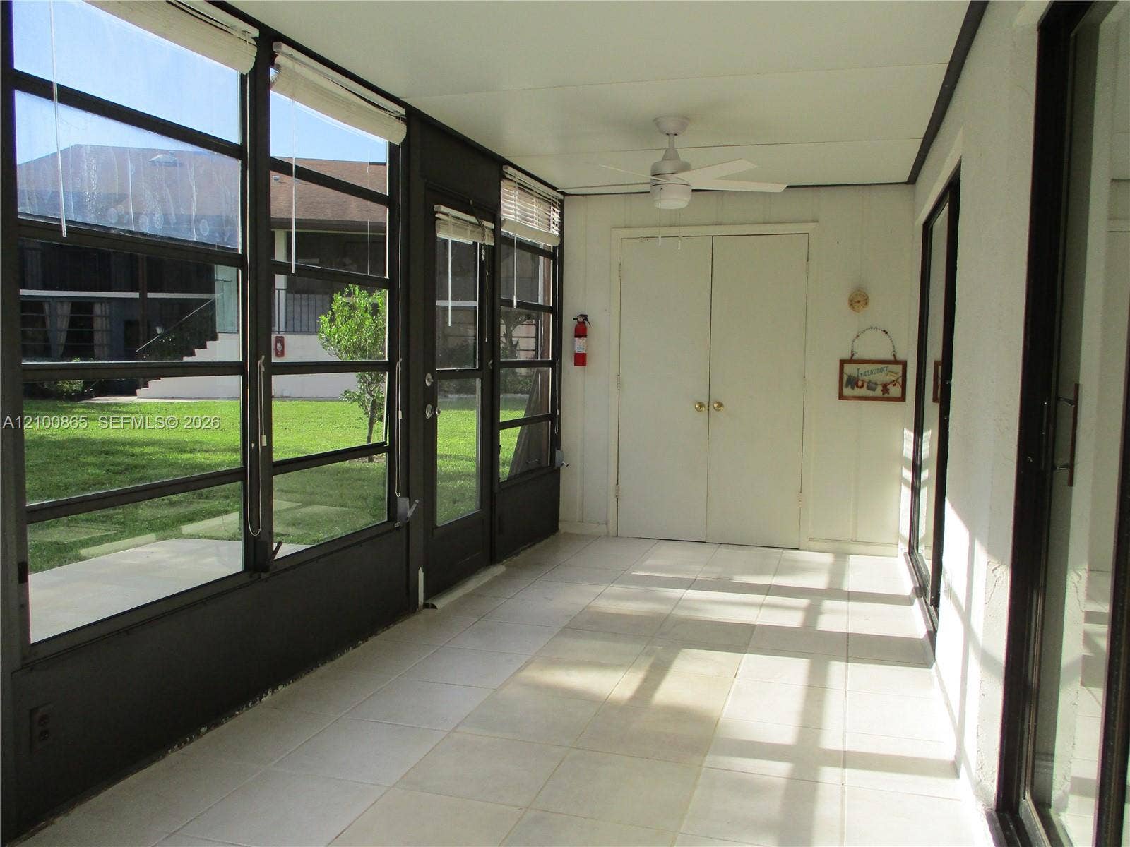 6531 SE Federal Highway, #J112, Stuart, FL 34997 Enclosed patio featuring tile flooring, full-height windows, a ceiling fan, and double doors, storage area at end with washer & dryer