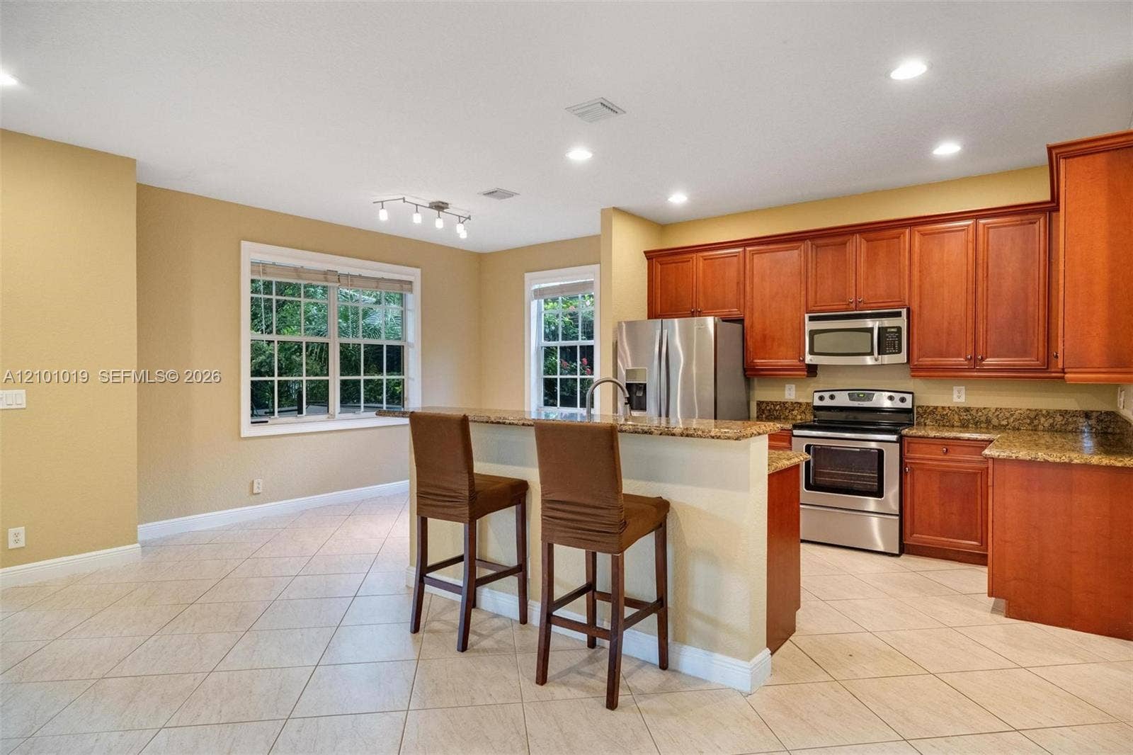 Kitchen featuring wooden cabinetry, stone-surface countertops, tile flooring, recessed lighting, and stainless steel appliances