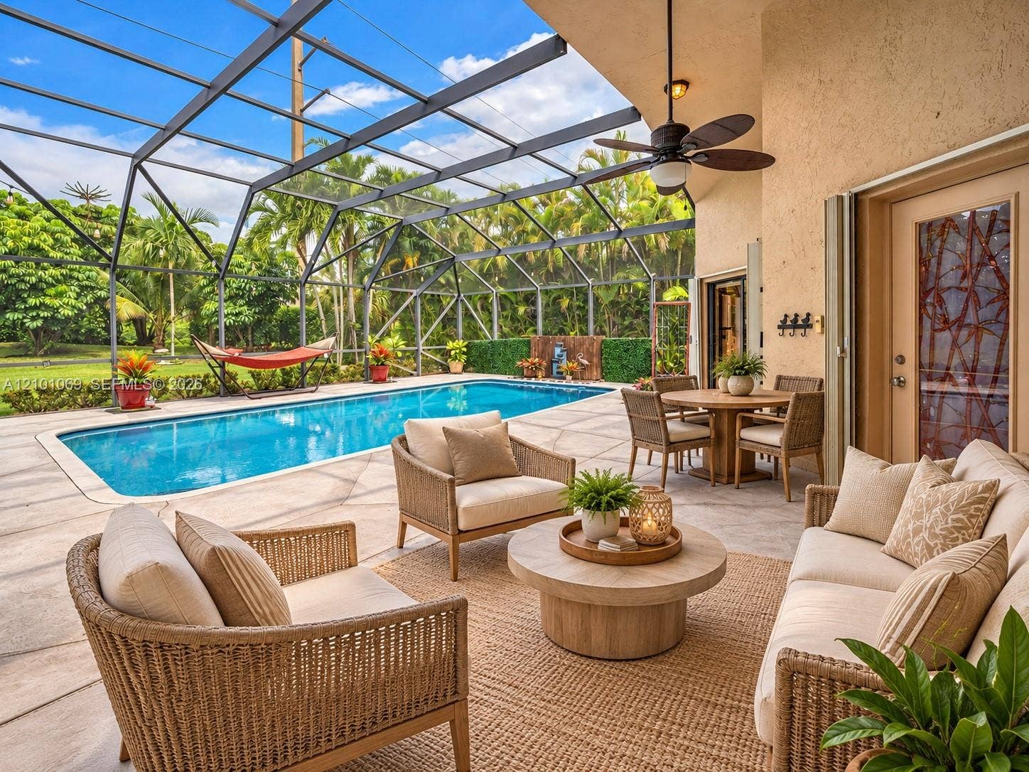 Screen-enclosed patio featuring a concrete deck, newly resurfaced swimming pool, and ceiling fan - virtually staged