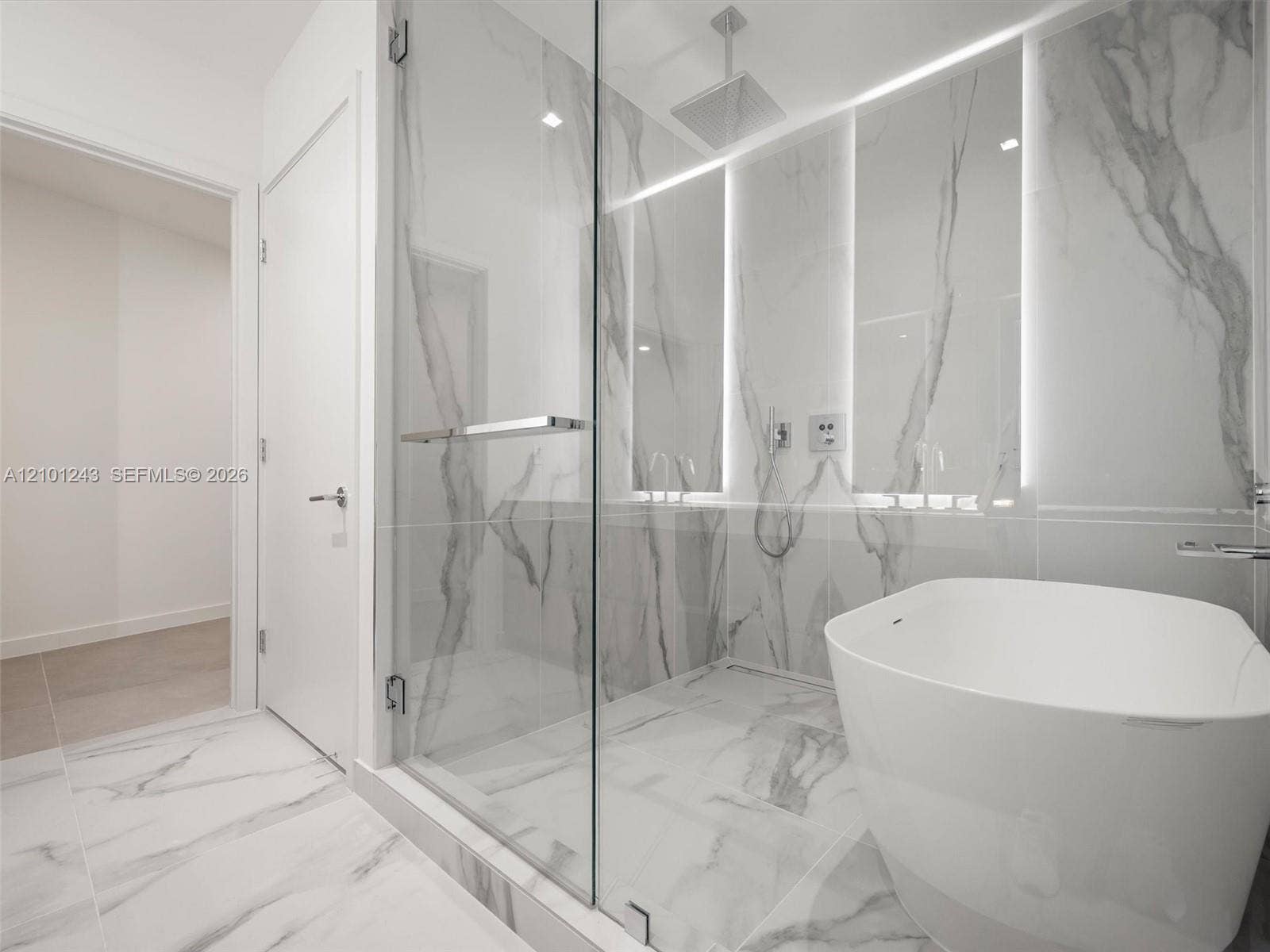 Glass-enclosed shower with large-format veined tile, integrated wall lighting, overhead rain shower head, and freestanding white soaking tub