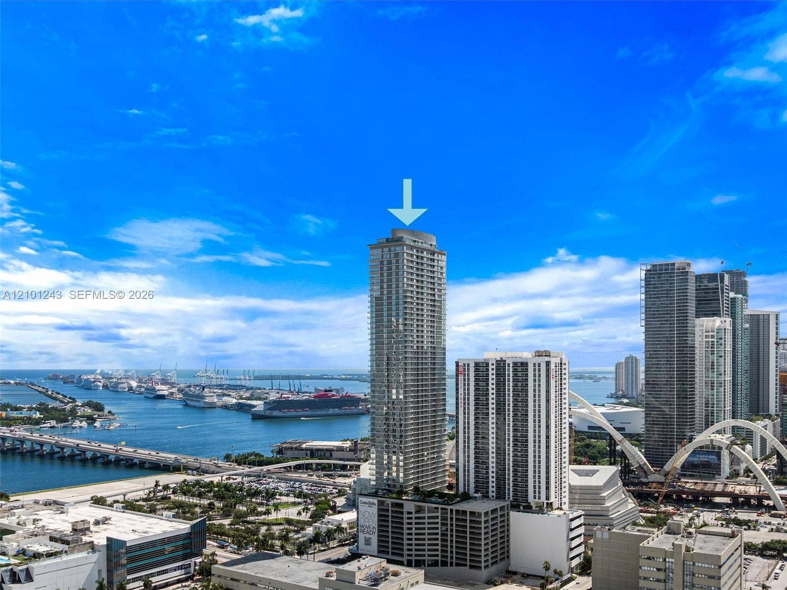 High-rise residential tower featuring a glass facade, private balconies, and a multi-level parking structure