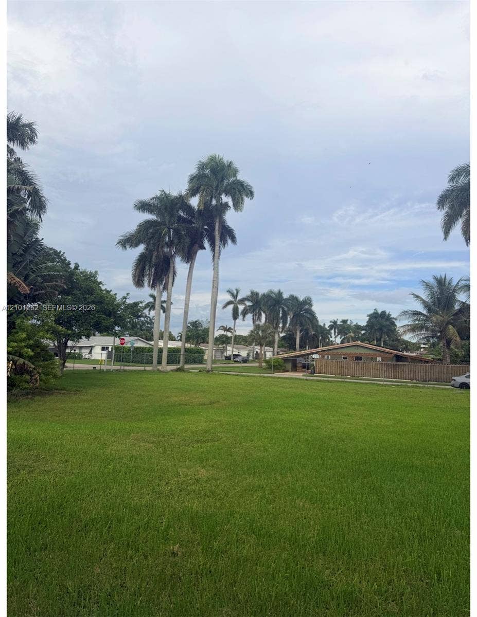 Expansive open lot featuring mature palm trees and established landscaping