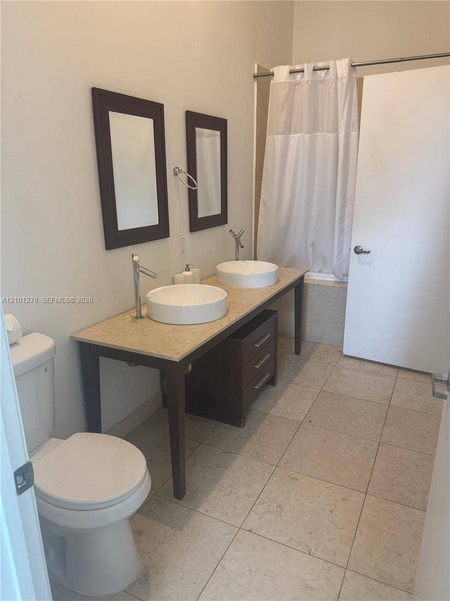 485 Brickell Avenue, #2806, Miami, Miami, FL 33131 Double vanity featuring vessel sinks, stone-finish countertop, dark wood-tone cabinetry, and large-format tile flooring