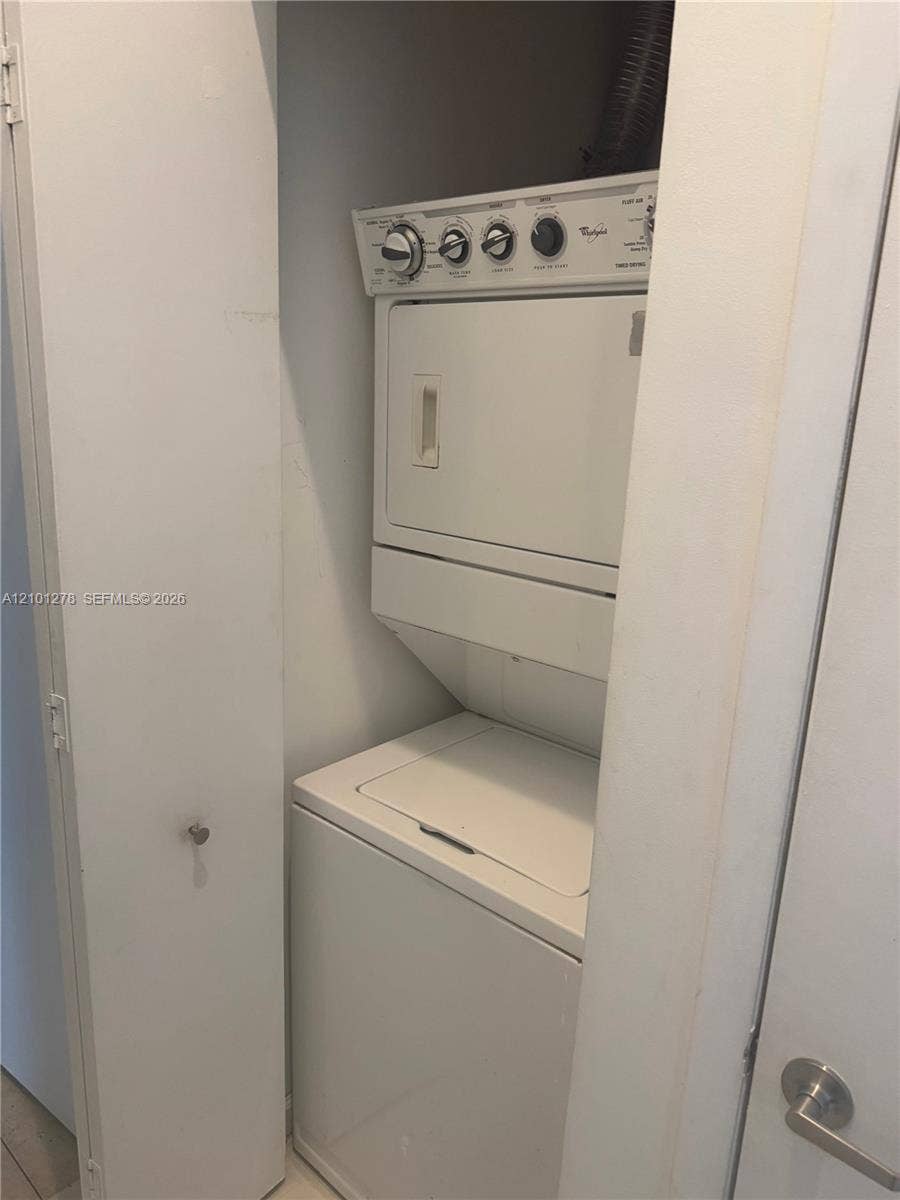 485 Brickell Avenue, #2806, Miami, Miami, FL 33131 Stacked laundry unit featuring a white top-loading washer and front-loading dryer enclosed within a closet