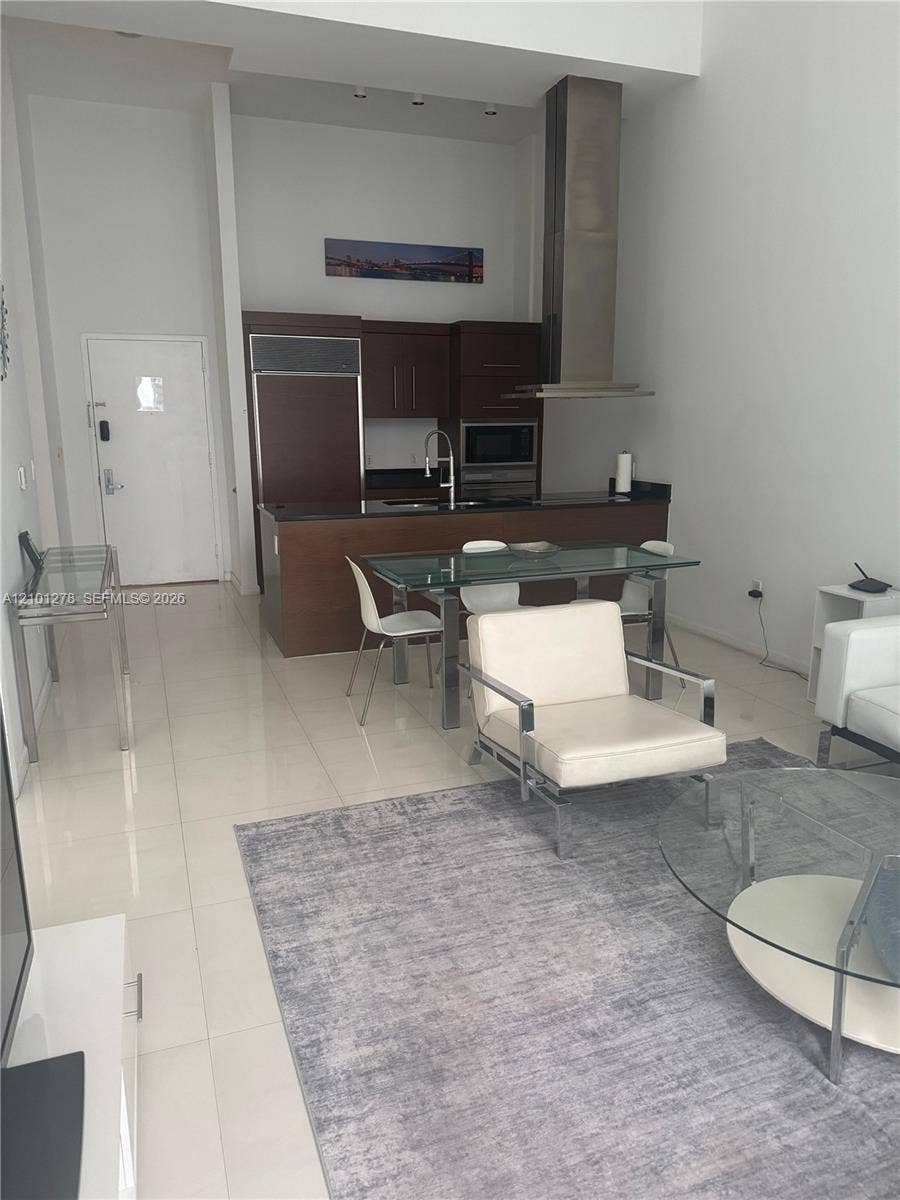 485 Brickell Avenue, #2806, Miami, Miami, FL 33131 High-ceiling interior featuring flat-panel dark wood cabinetry, stainless steel range hood, stone countertops, and polished tile flooring