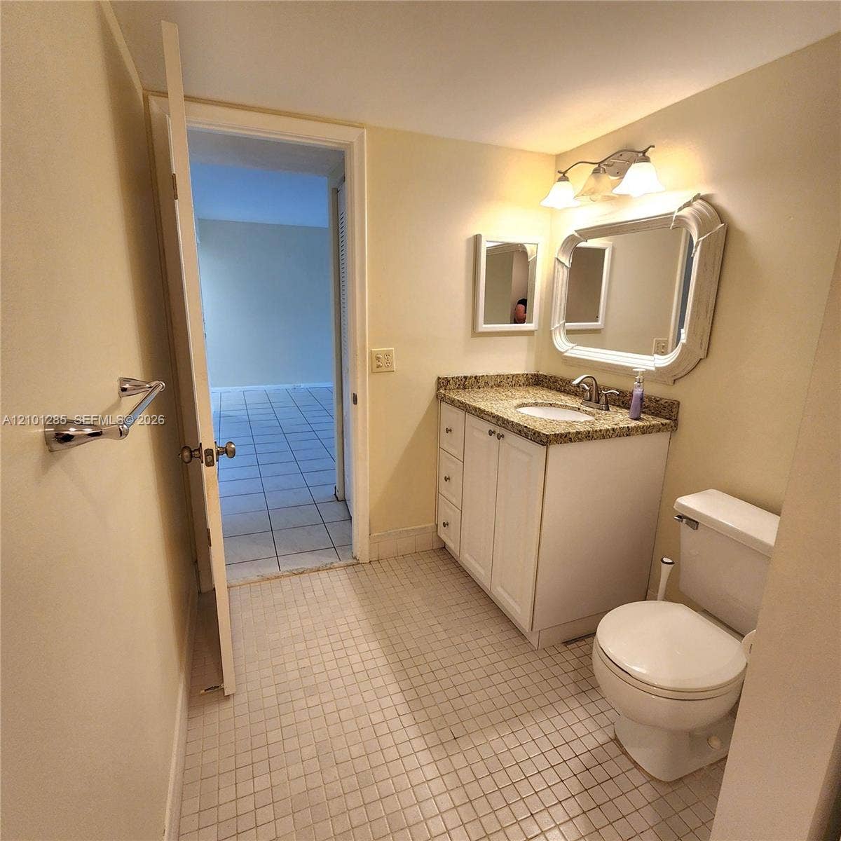 Bathroom featuring a vanity with stone-finish countertop, undermount sink, decorative wall mirror, and ceramic tile flooring