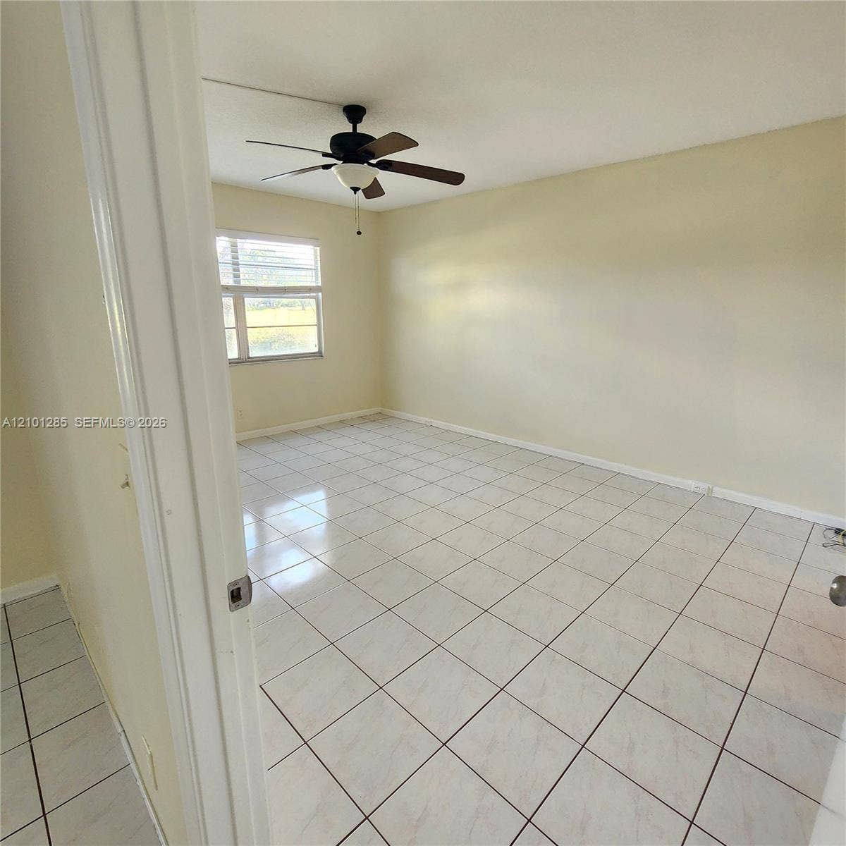 Interior space featuring neutral wall paint, large-format tile flooring, and a multi-blade ceiling fan with an integrated light fixture