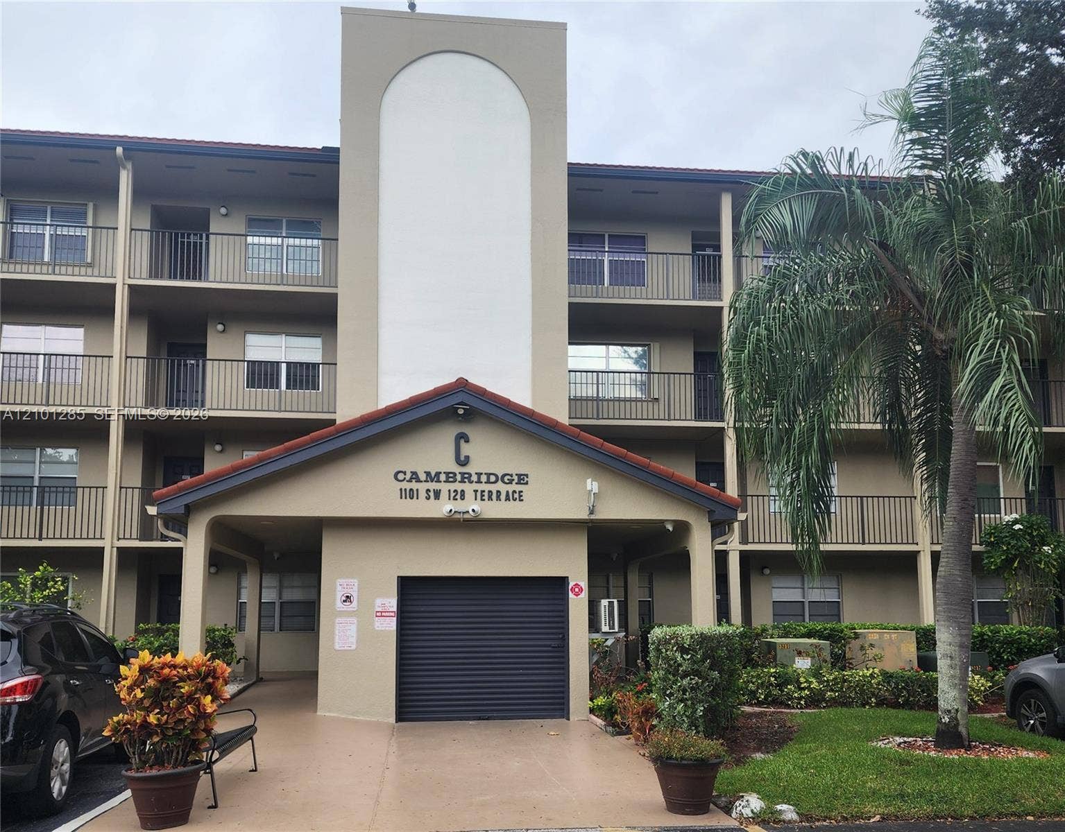 Multi-story building exterior featuring a tiled gable roof, private balconies with metal railings, and a central architectural tower element
