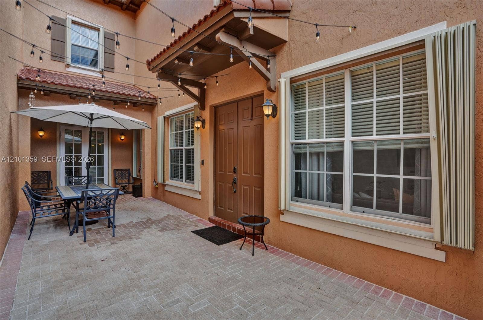 859 SW 147th Terrace, #0, Pembroke Pines, FL 33027 Enclosed courtyard featuring a paved brick patio, double entry doors, clay-tile roofing accents, and wall-mounted exterior lighting