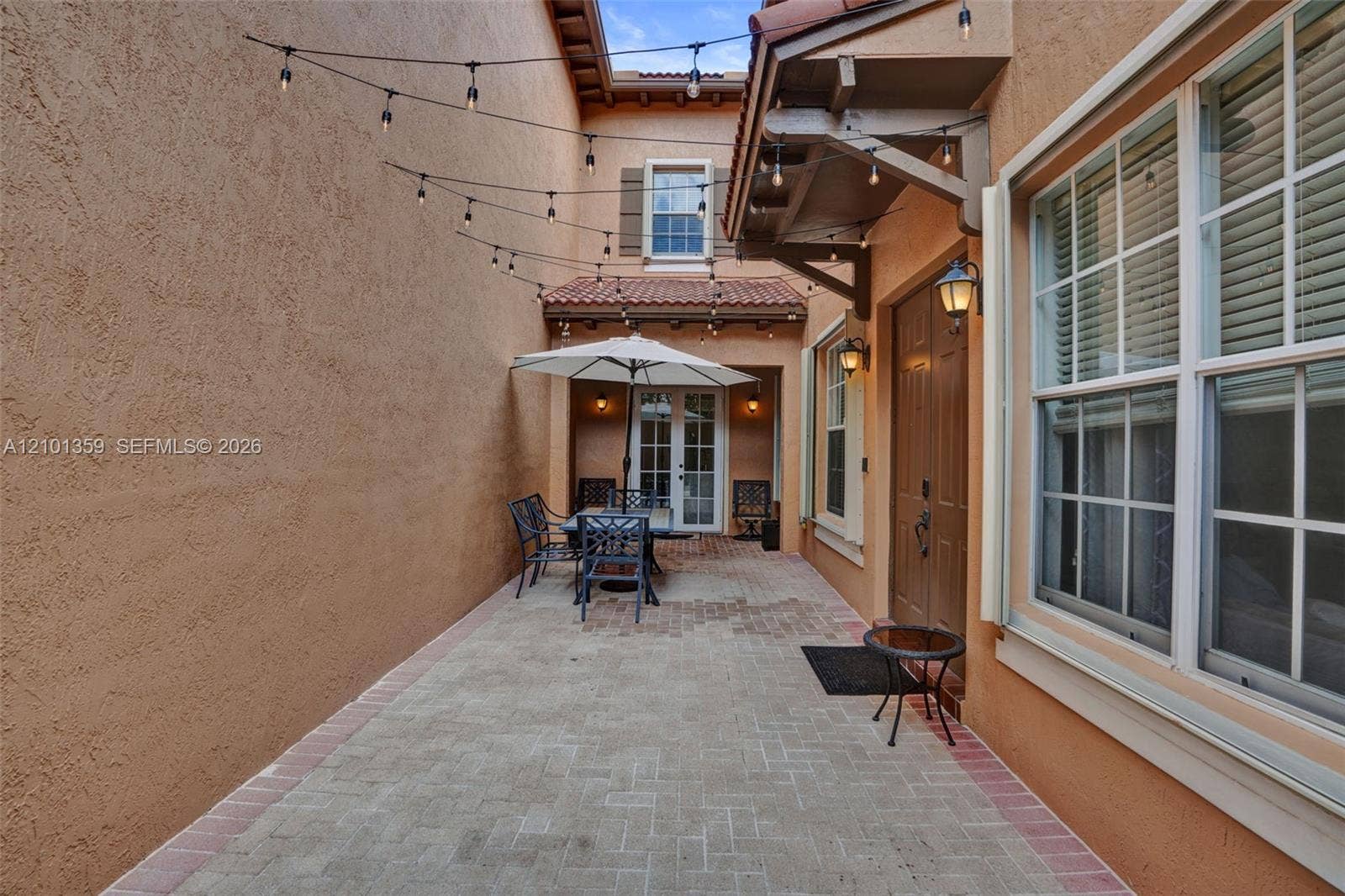 859 SW 147th Terrace, #0, Pembroke Pines, FL 33027 Enclosed courtyard featuring herringbone-patterned brick pavers, dual entry doors, multi-pane windows, and a clay tile roof