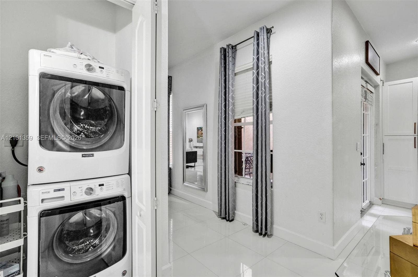 859 SW 147th Terrace, #0, Pembroke Pines, FL 33027 Laundry area featuring stacked front-load appliances, tile flooring, window with blind, and built-in cabinetry