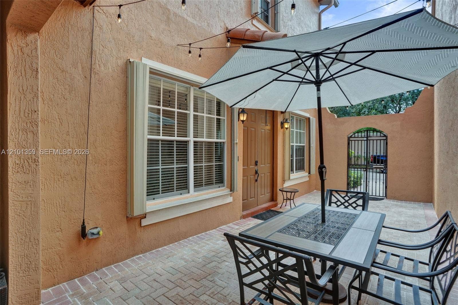 859 SW 147th Terrace, #0, Pembroke Pines, FL 33027 Stucco exterior courtyard featuring herringbone-patterned paver flooring, double-entry doors, and a decorative wrought-iron gate