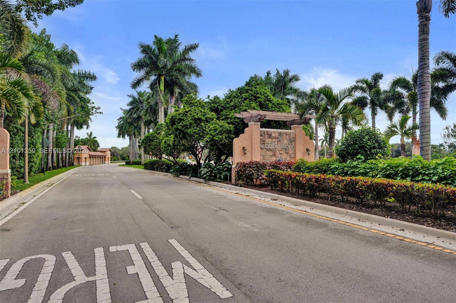 859 SW 147th Terrace, #0, Pembroke Pines, FL 33027 Stone-accented community monument signage featuring a wood-beam pergola, paved private roadway, and mature landscaping with established palm trees