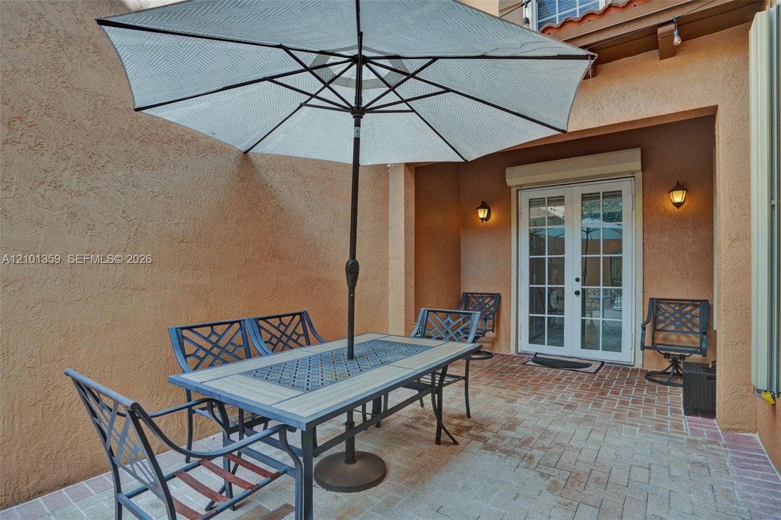 859 SW 147th Terrace, #0, Pembroke Pines, FL 33027 Enclosed patio featuring stucco walls, paver flooring, French doors, and wall-mounted exterior lighting